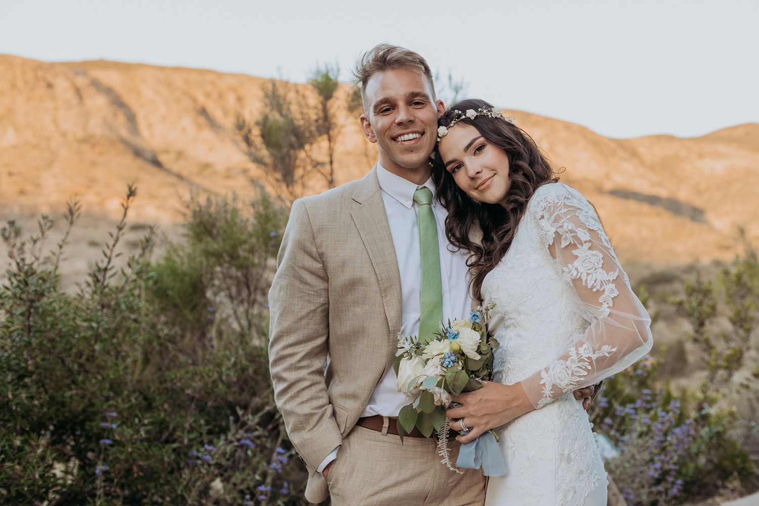 A couple poses together against desert mountains during golden hour at Mission Trails Community Center in San Diego.