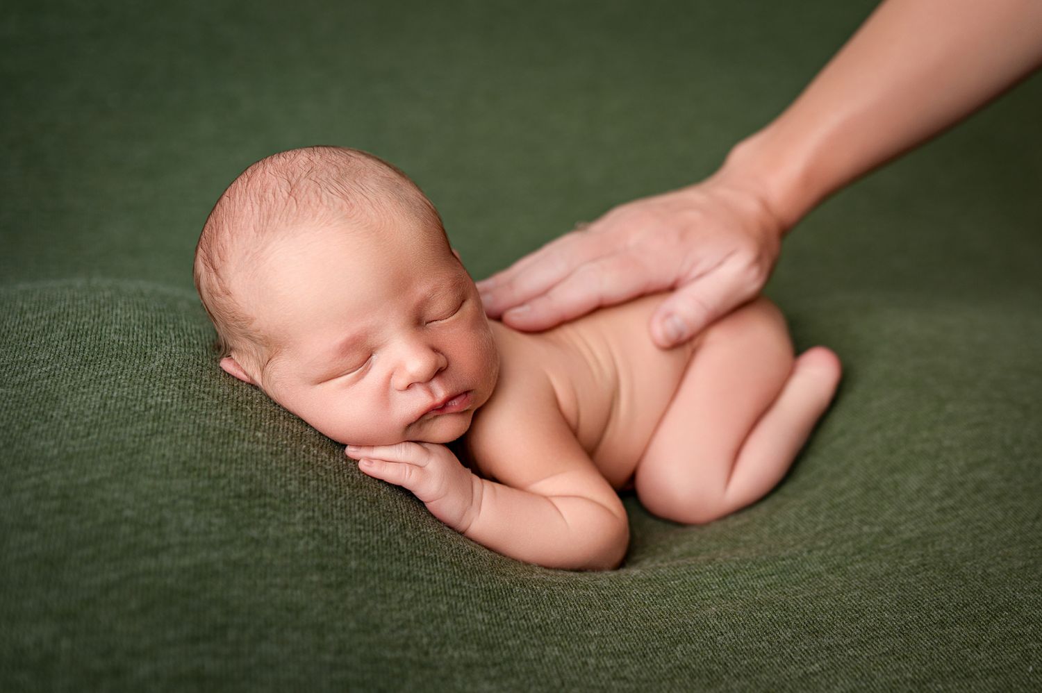 A sleeping newborn wrapped in white swaddle on floral background reflective surface for professional portrait photography.