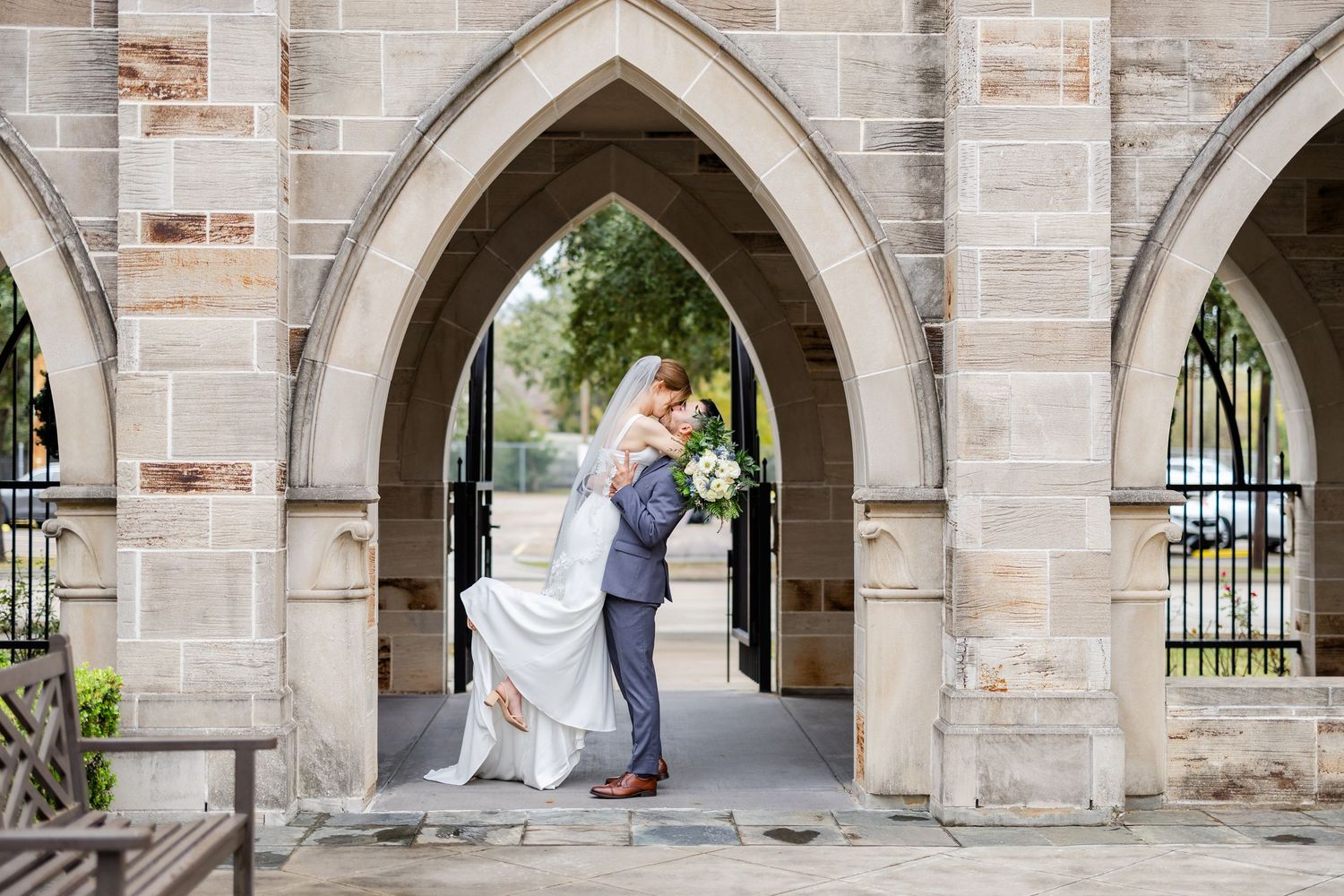 A romantic couple shares a loving moment under gothic stone arches on their wedding day.