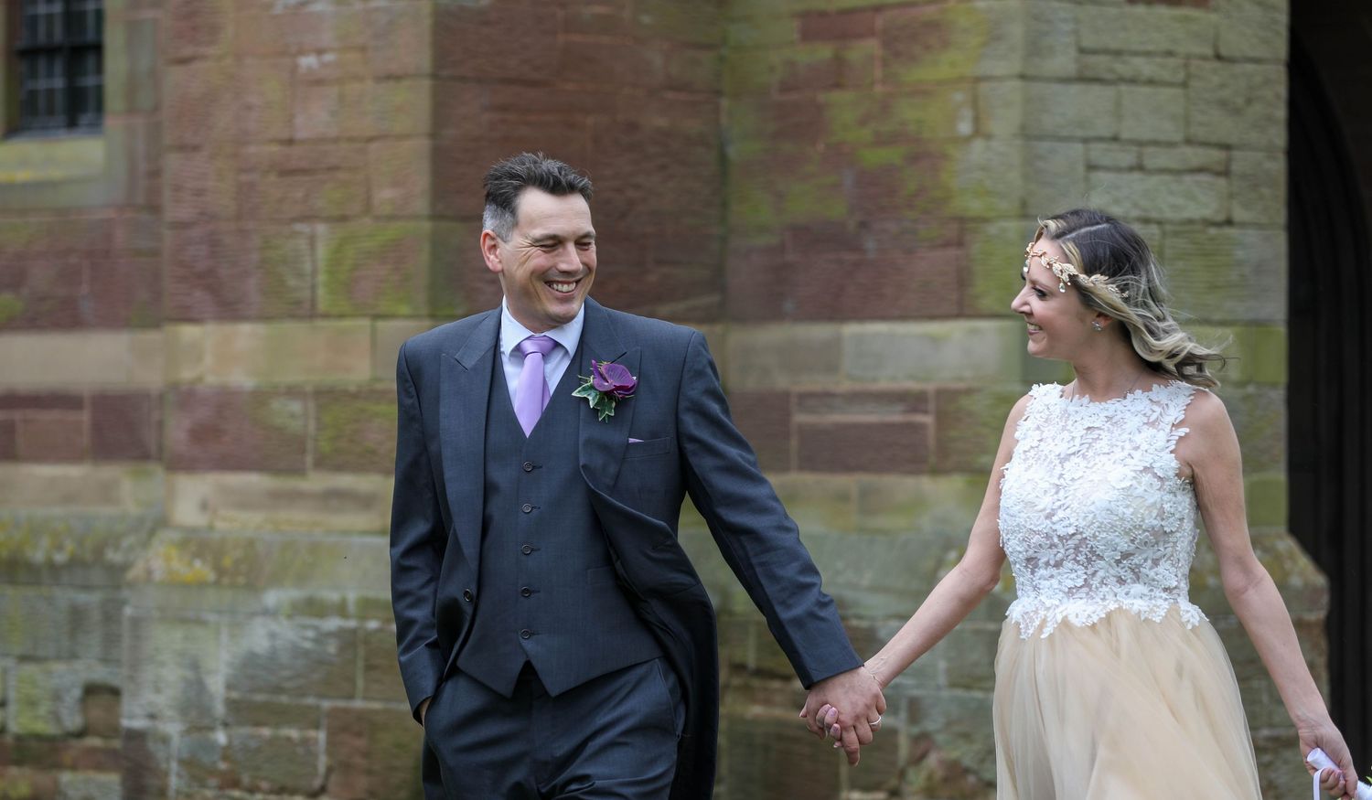 Wedding portraits captured against rustic brick wall backdrop.