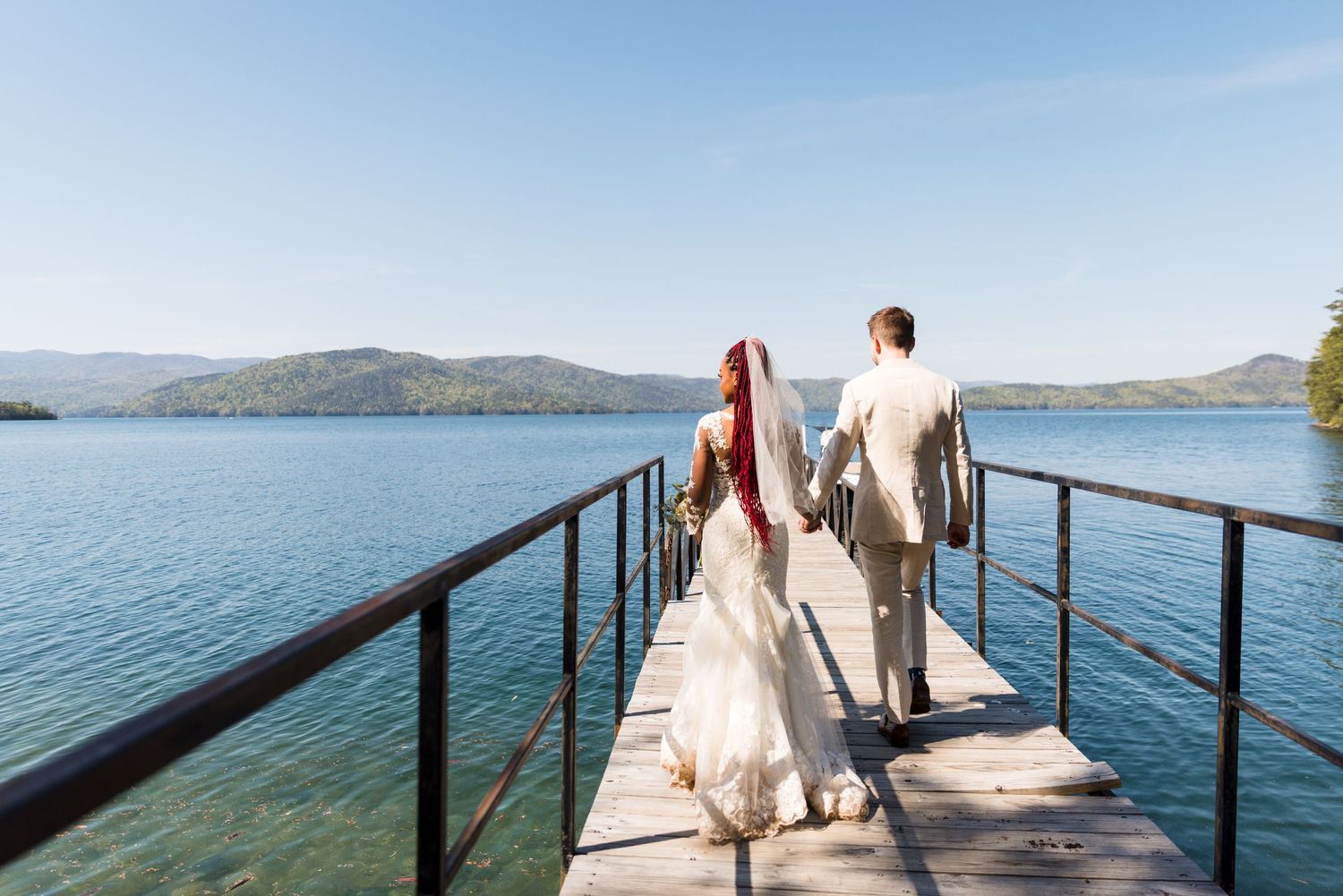 Wedding party poses on a wooden dock overlooking a serene mountain lake.