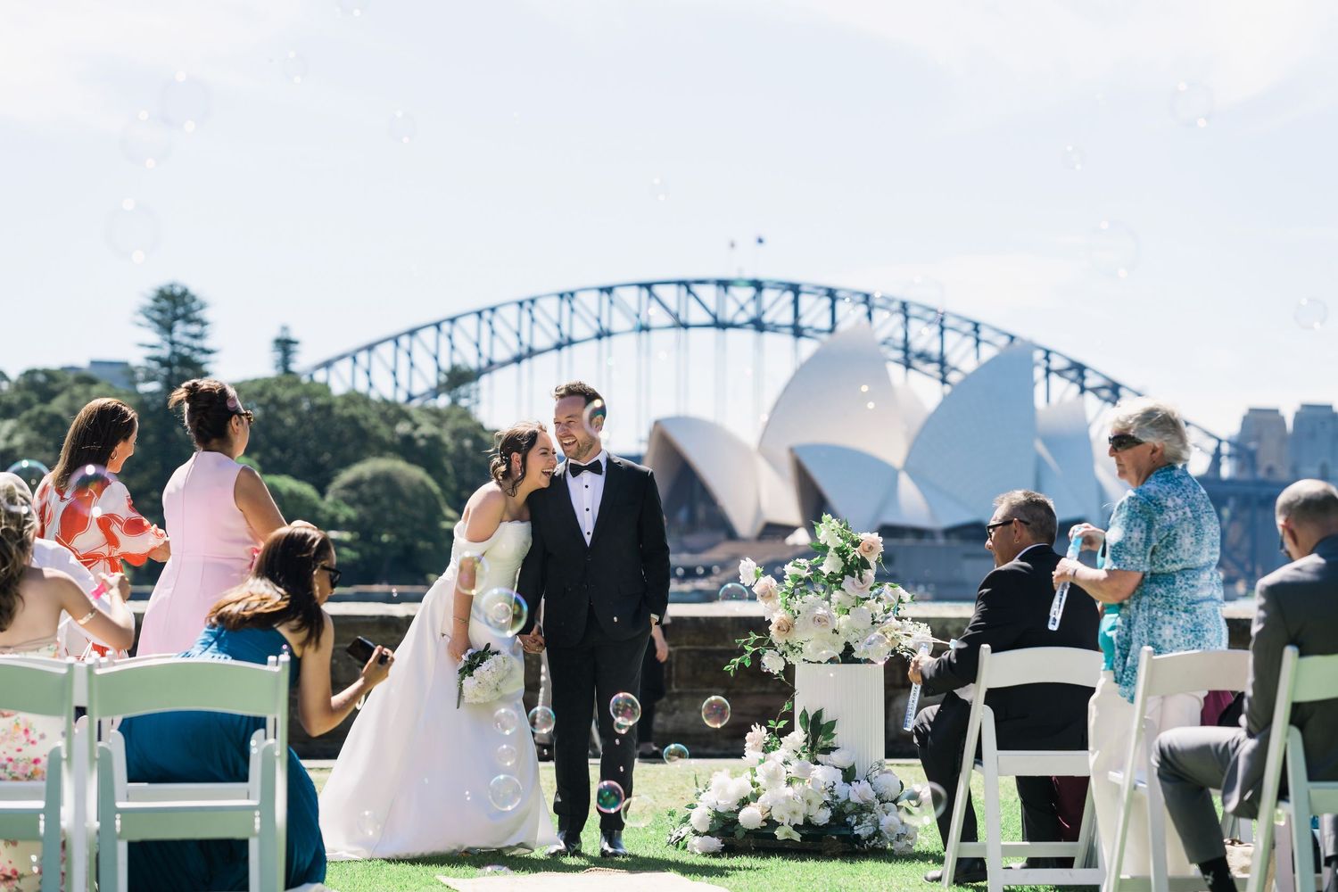 Bride and groom leaving a Royal Botanic Garden Sydney wedding with the Opera House and Harbour Bridge behind them