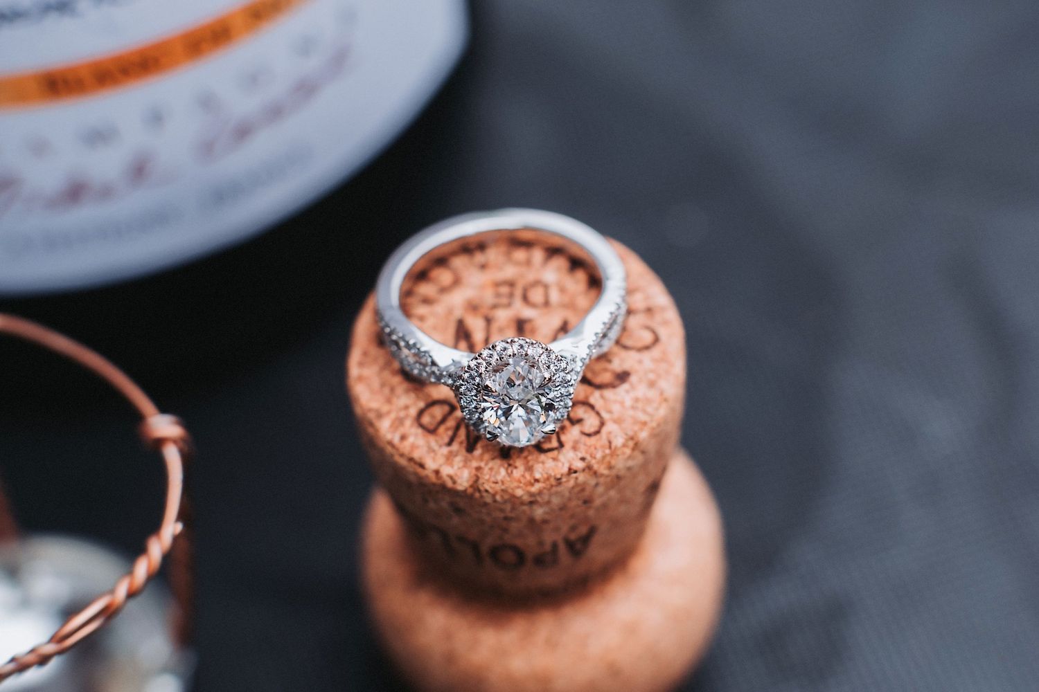 Silver diamond engagement ring rests on a rustic cork surface, capturing a romantic moment in soft lighting.