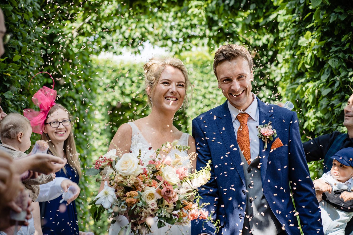 A happy couple walks through confetti during their outdoor garden wedding celebration at the Tangled Garden venue, Grand Pre, Nova Scotia