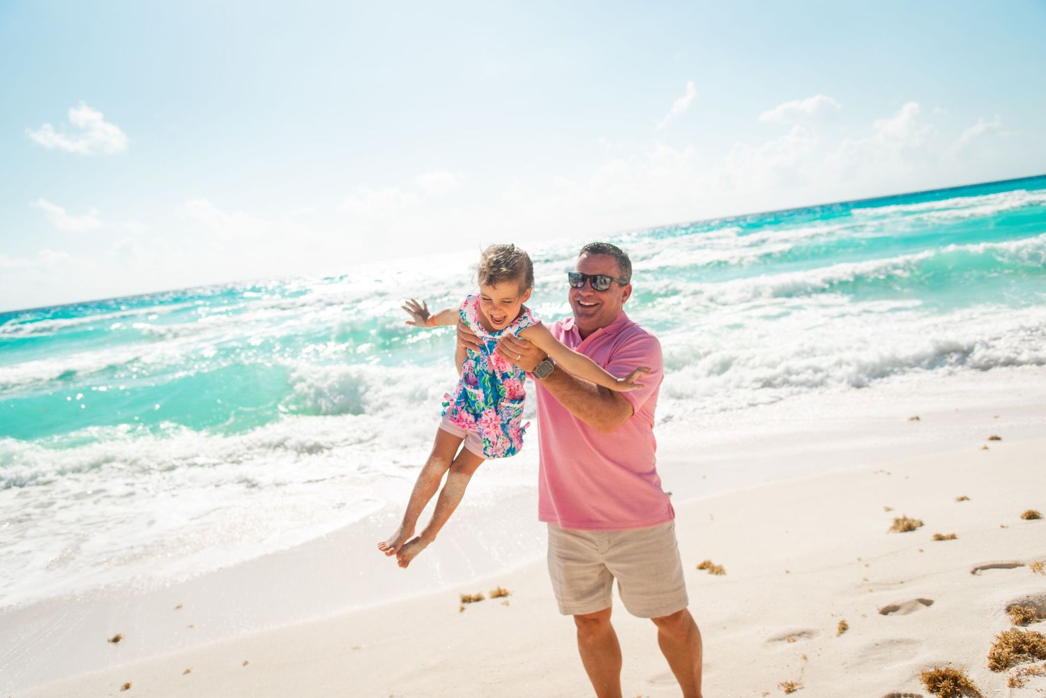 Tony carrying his daughter playing and making her fly during their beach family photoshoot in Cancun