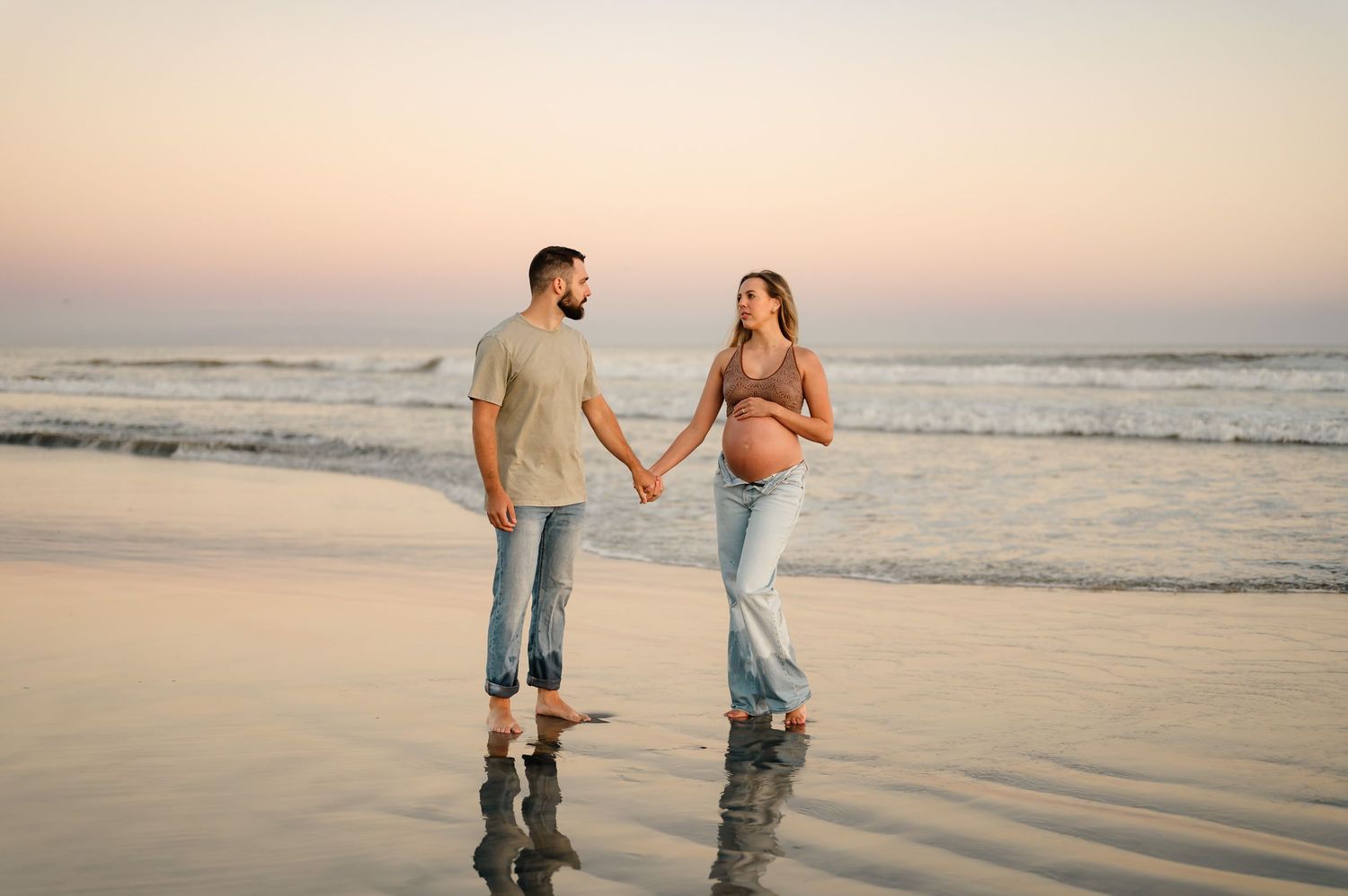 Santa Barbara babymoon maternity photoshoot on Carpinteria beach, of couple standing in water, by Ventura maternity photographer