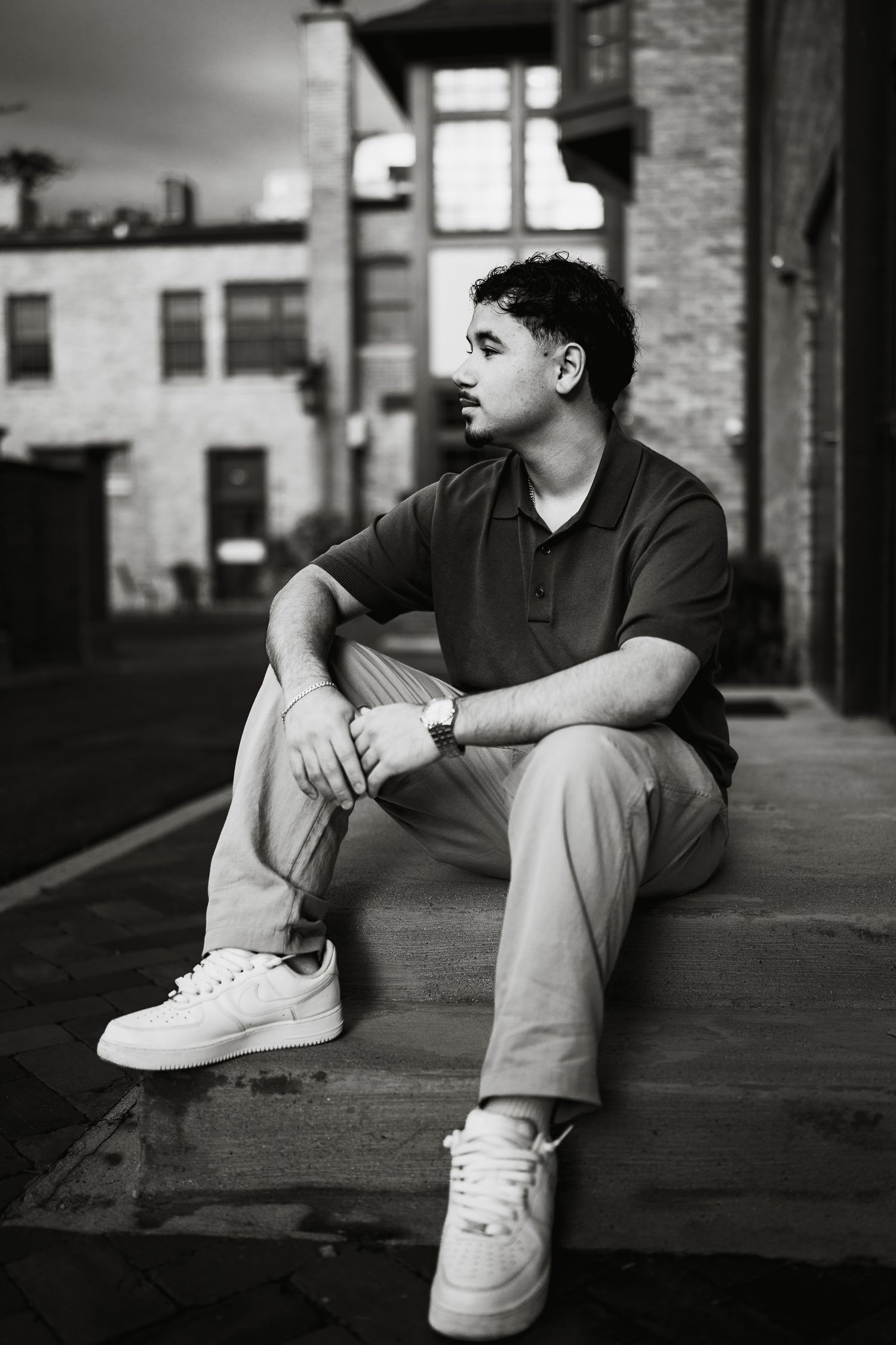Senior sitting on steps in urban setting, wearing polo shirt and white sneakers in Lake Forest