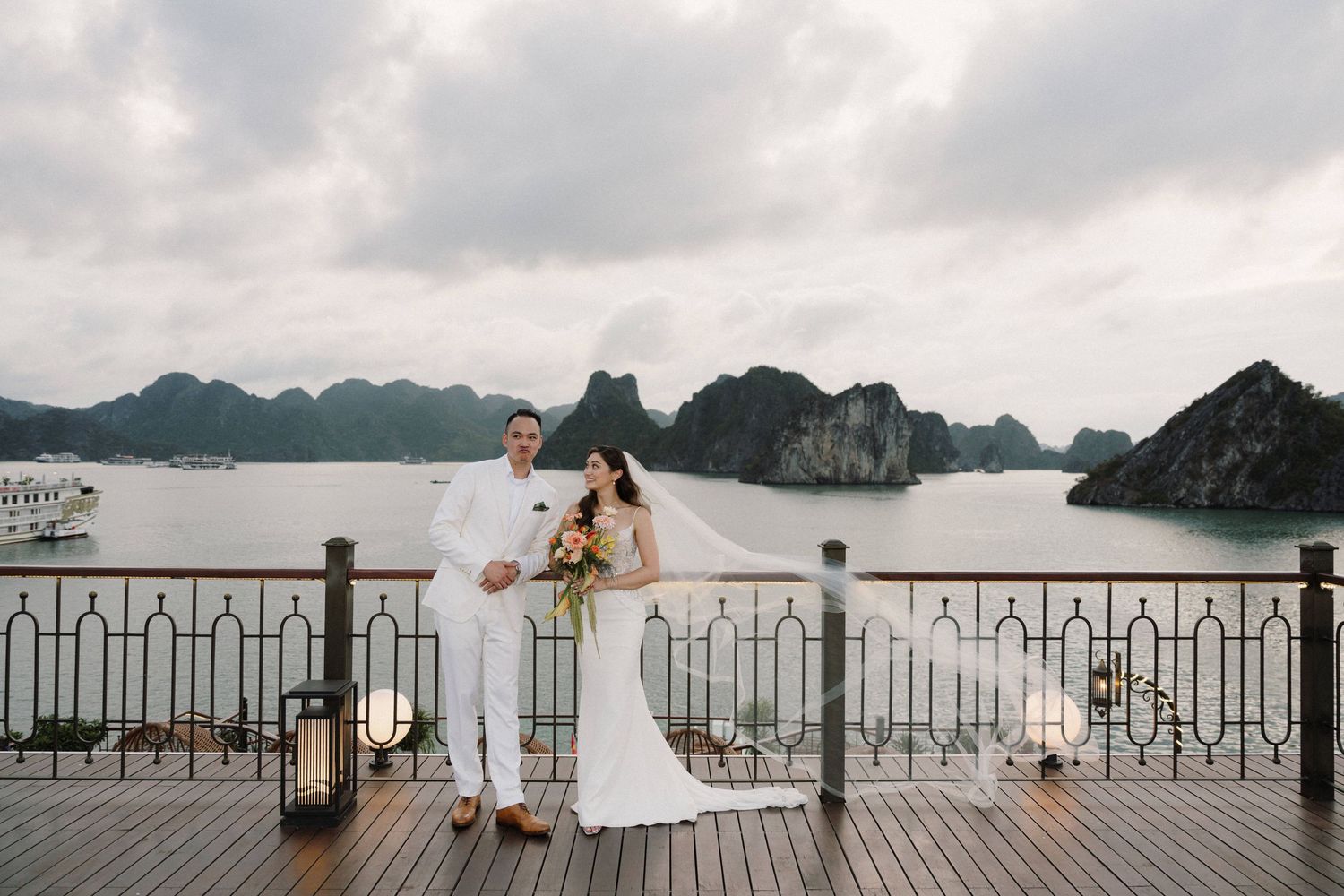 A scenic view of Ha Long Bay in Vietnam with limestone karsts rising from emerald waters under cloudy skies.