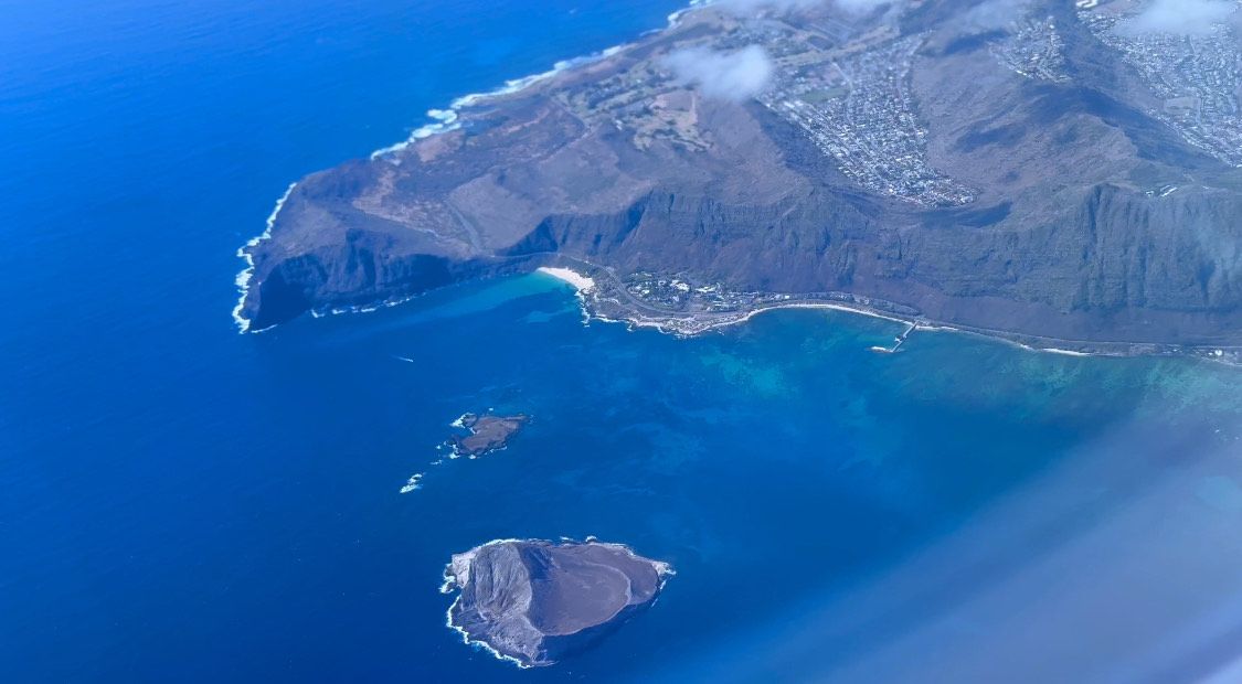 Aerial panoramic view of rugged coastal cliffs meeting vibrant blue Mediterranean waters along a scenic shoreline.