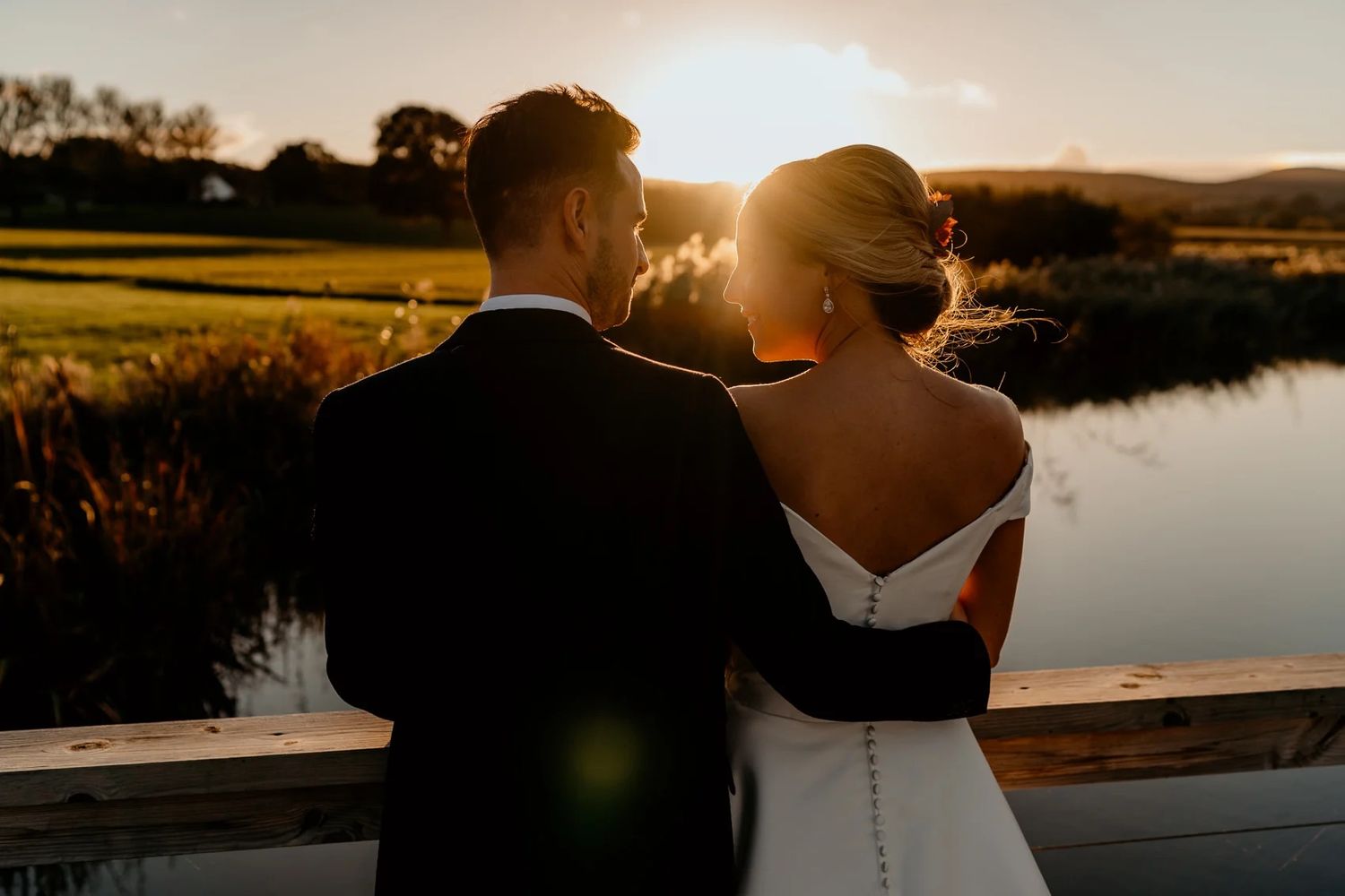 Wedding ceremony setup in rustic wooden barn with white floral arrangements and natural lighting.