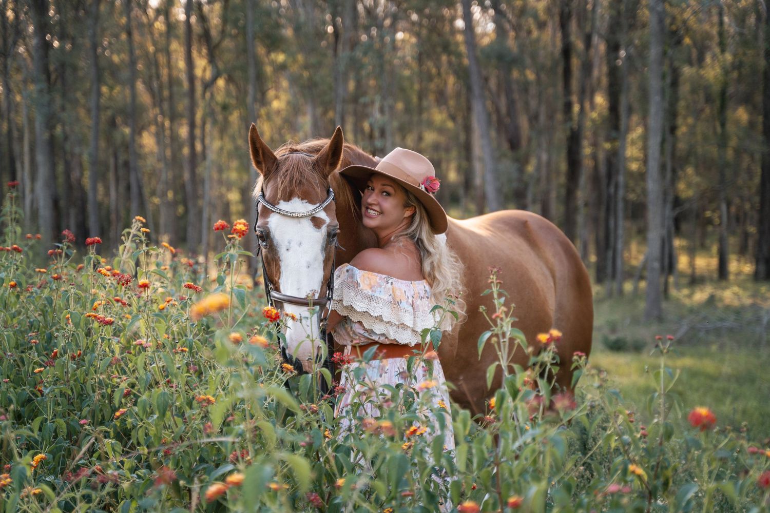 A brown horse stands in a field of wildflowers and tall grass during autumn portrait photoshoot with a woman in Sydney horse photoshoot