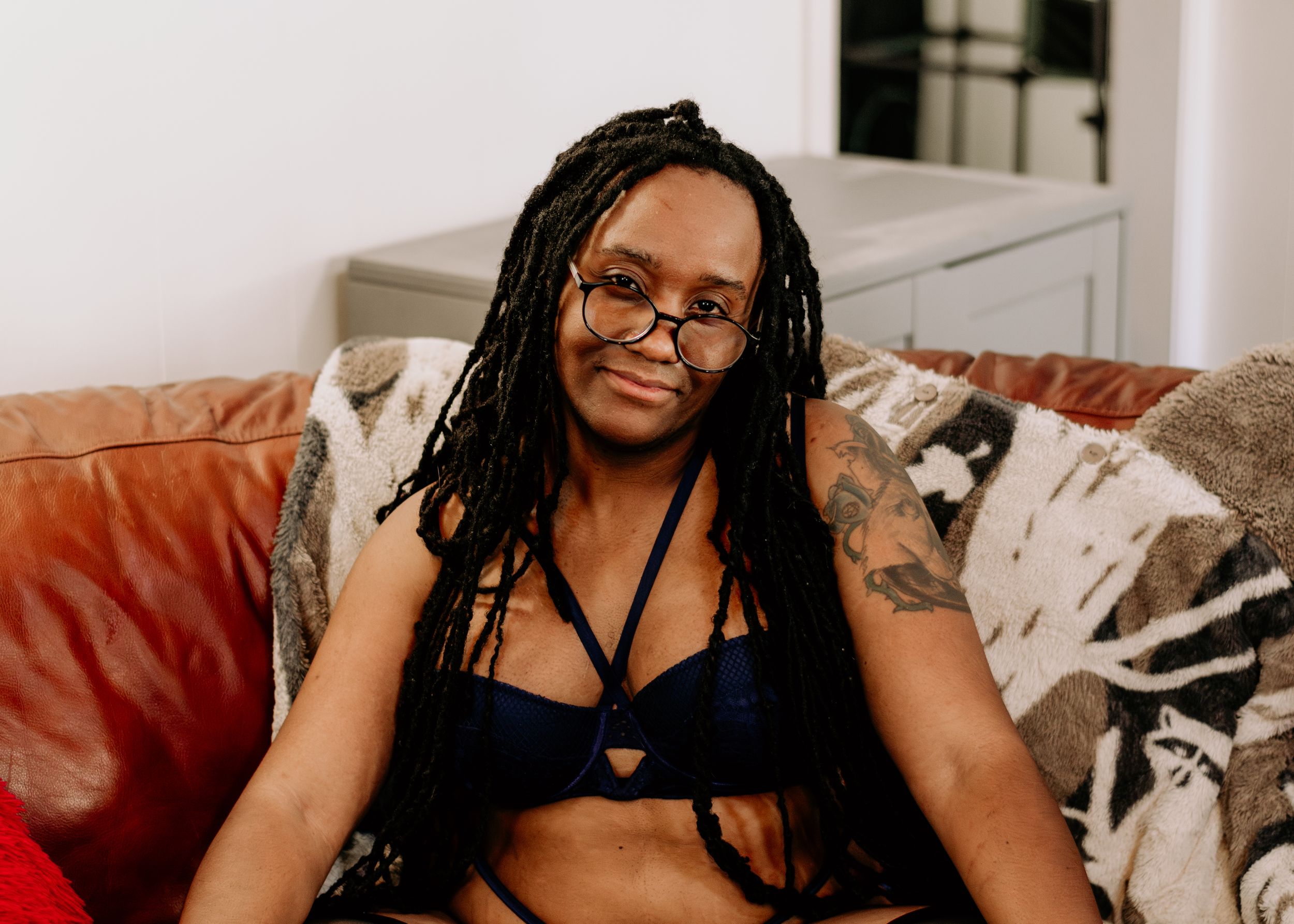 Person in black crop top poses on rattan chair with festive decor.