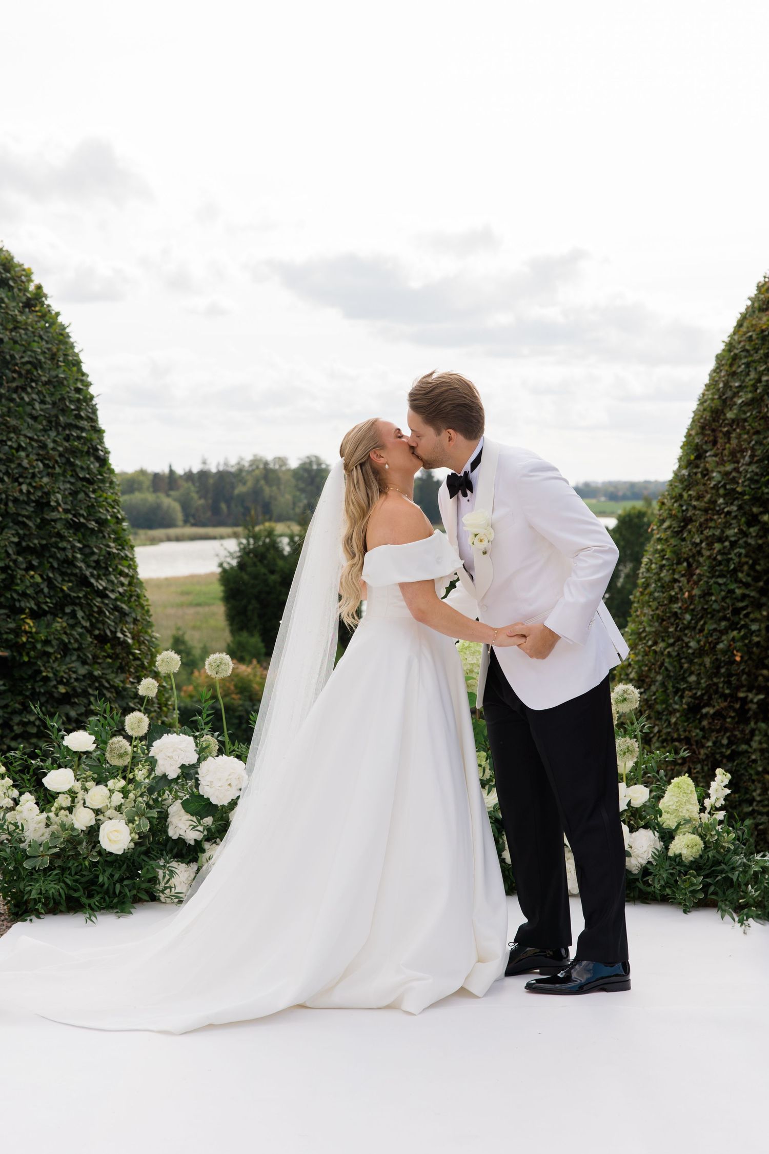 Bride and groom pose together on stone steps outside a grand yellow manor house in a series of romantic wedding photos.