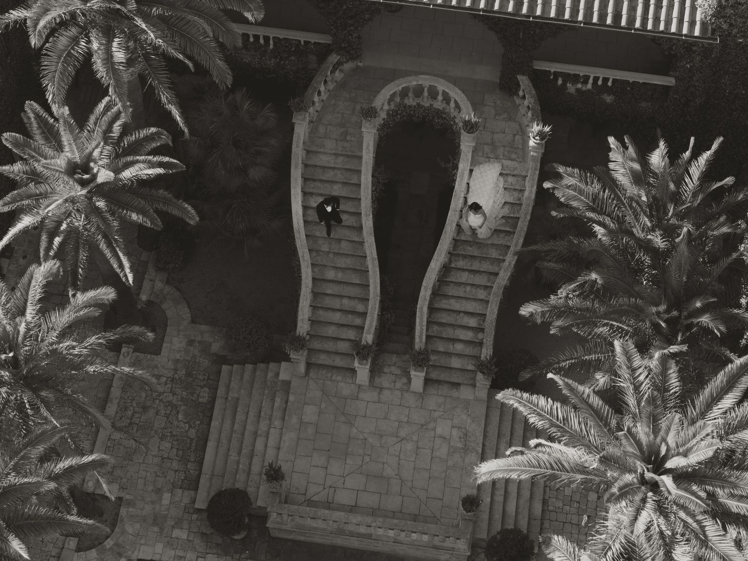 A black and white photo of a wedding cake displayed on a table with sparkling firework fountains in the background.