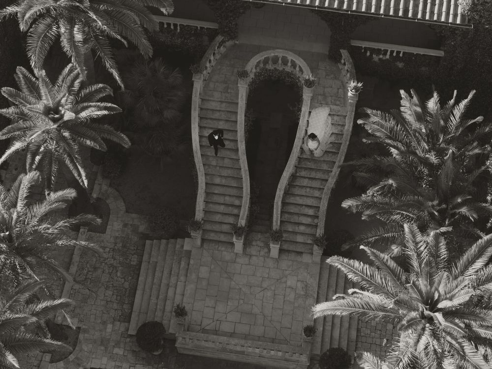 A black and white photo of a wedding cake displayed on a table with sparkling firework fountains in the background.
