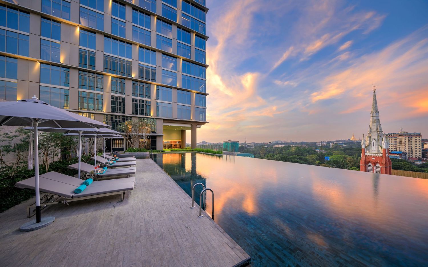 A panoramic sequence of modern waterfront buildings and walkways at sunset with vibrant orange and purple skies.