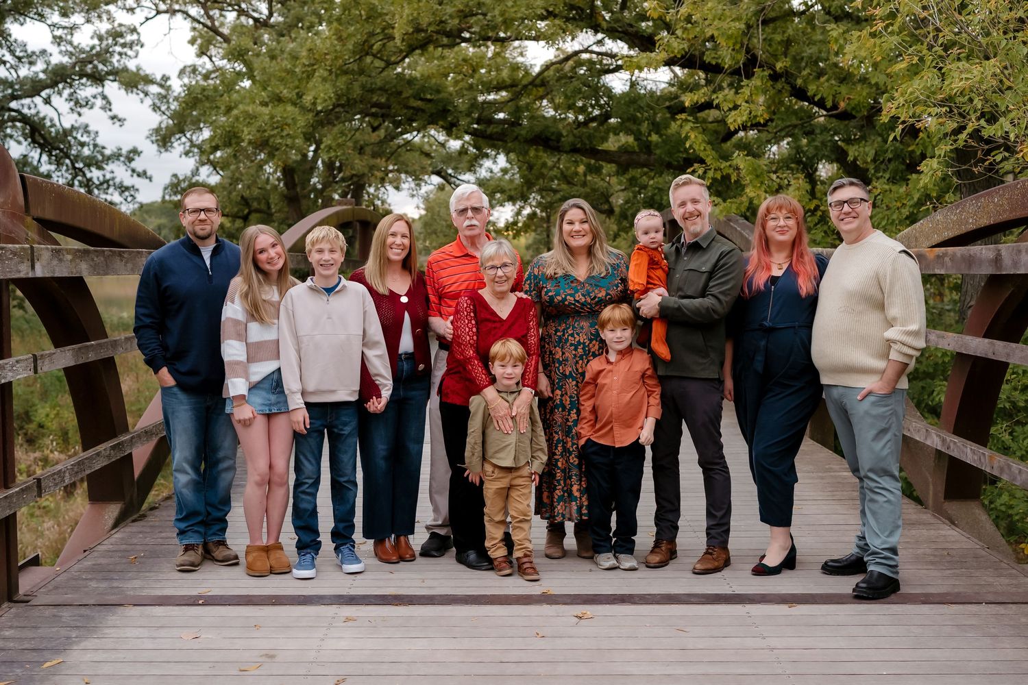 A group of people sitting casually on wooden steps in an outdoor setting during a photo session.
