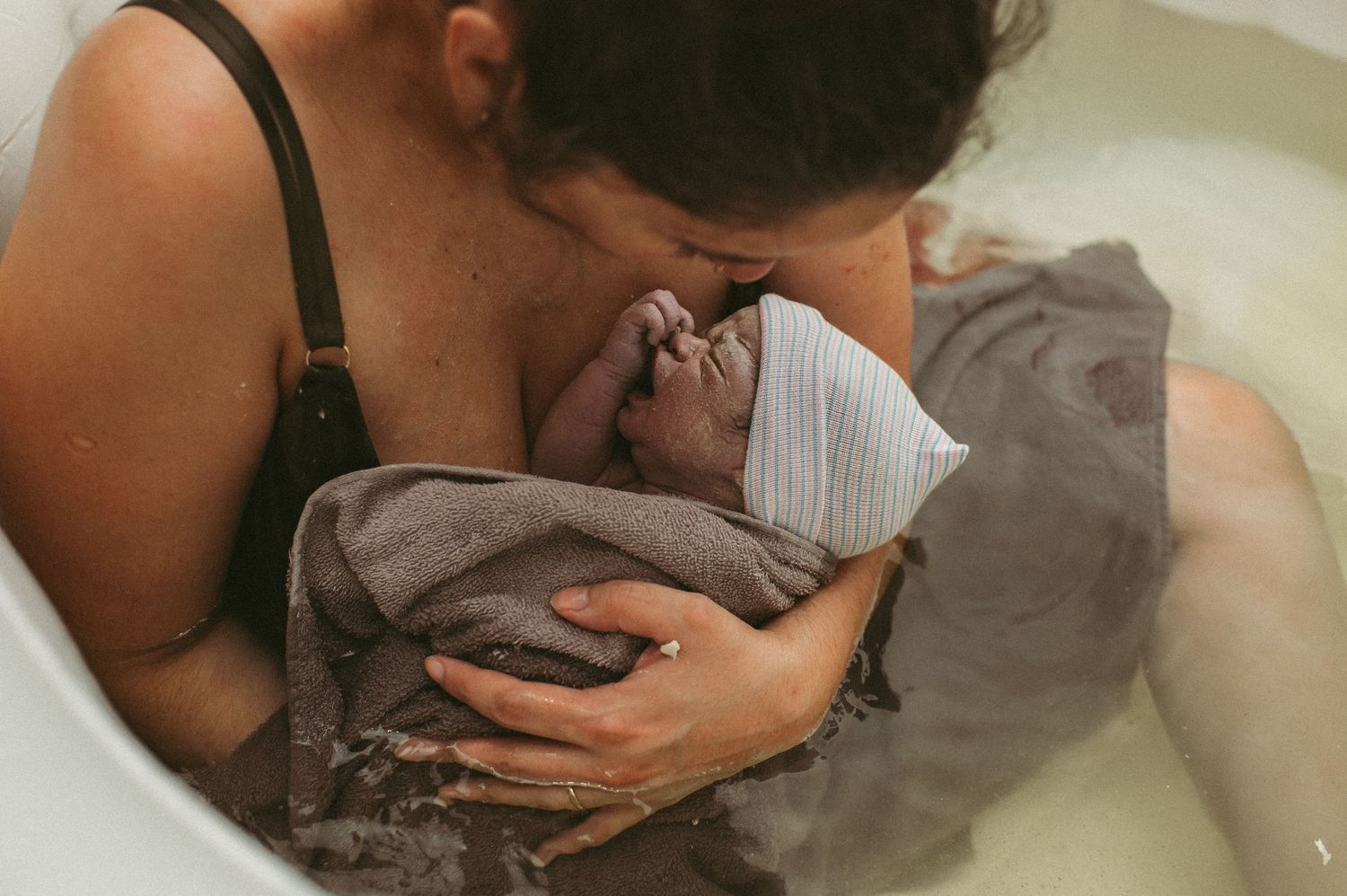 Hampton, VA mom cradling her brand new baby boy in her home in a birthing pool.
