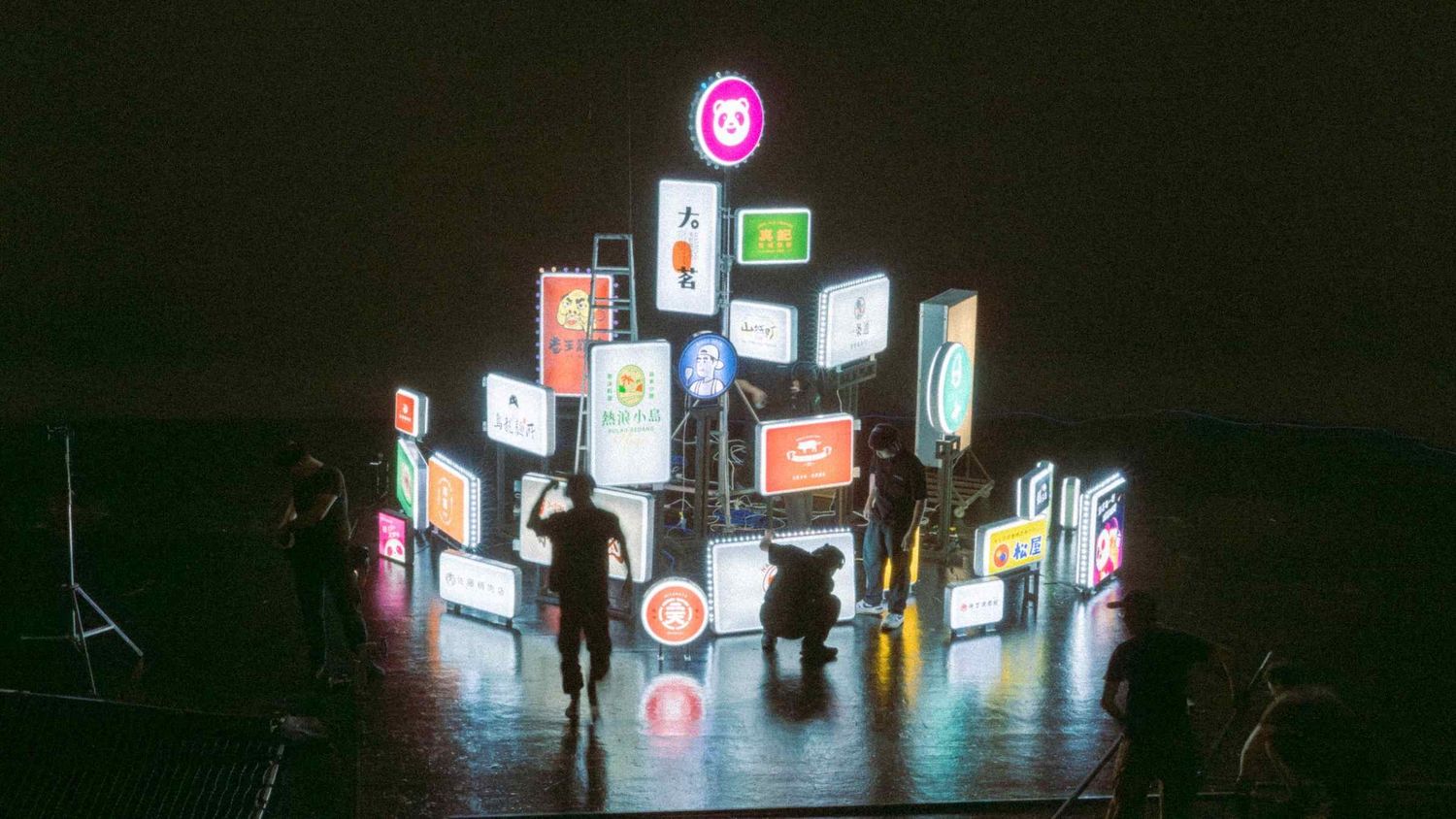 Neon signs illuminate a vibrant nighttime street scene in an Asian city with colorful storefronts and glowing advertisements.