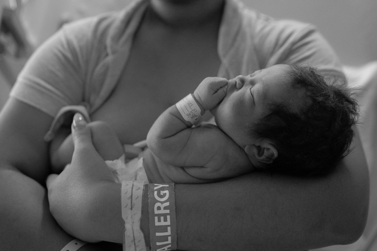 A black and white sequence of images showing a newborn baby being held and comforted in a medical setting.