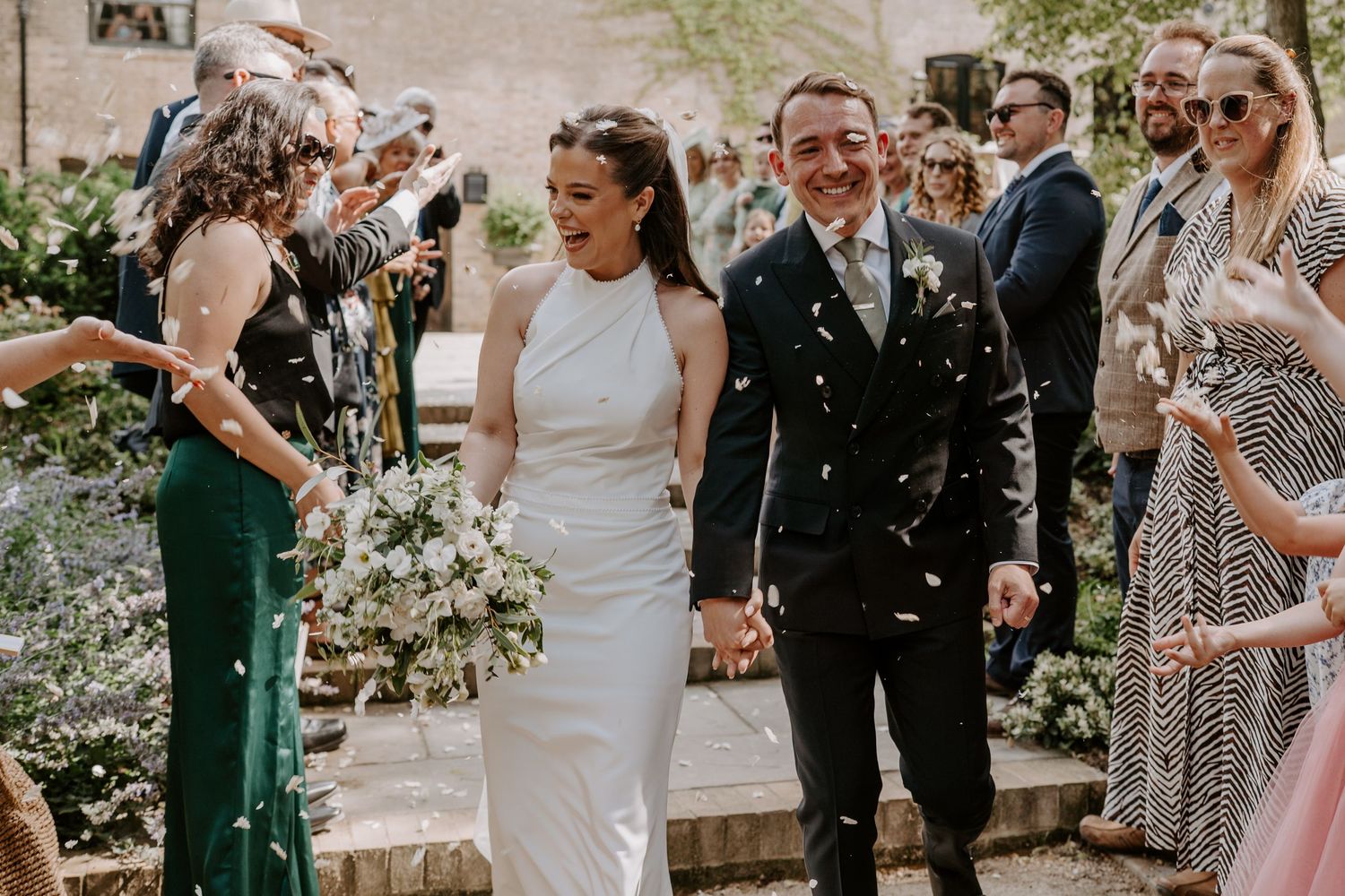 An outdoor wedding ceremony area in the courtyard of Shotesham Park. Big florals in orange and pink are displayed in clay pots.