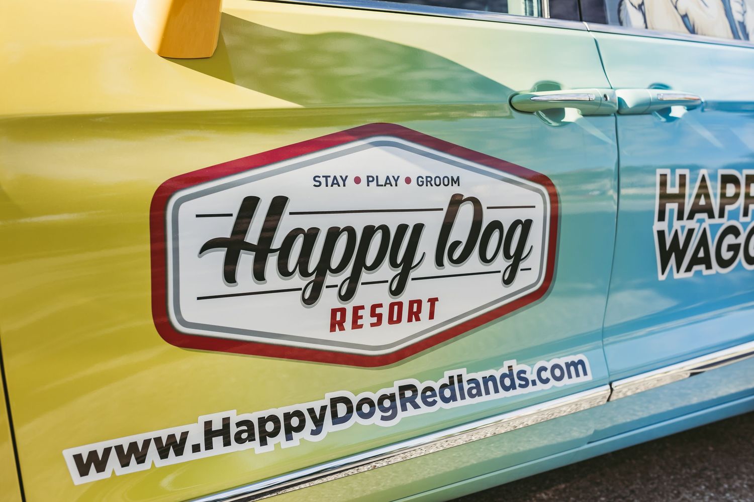 Happy Dog Resort logo and HappyDogRedlands.com website decal on the side of a yellow-green pet service van.