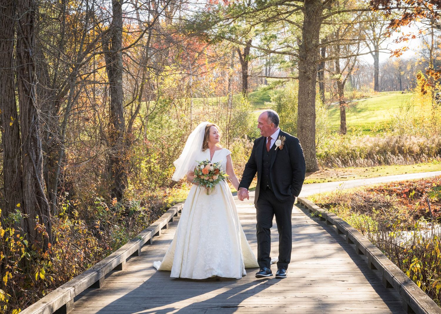A winter wedding portrait outside a white farmhouse with illuminated windows and a full moon.