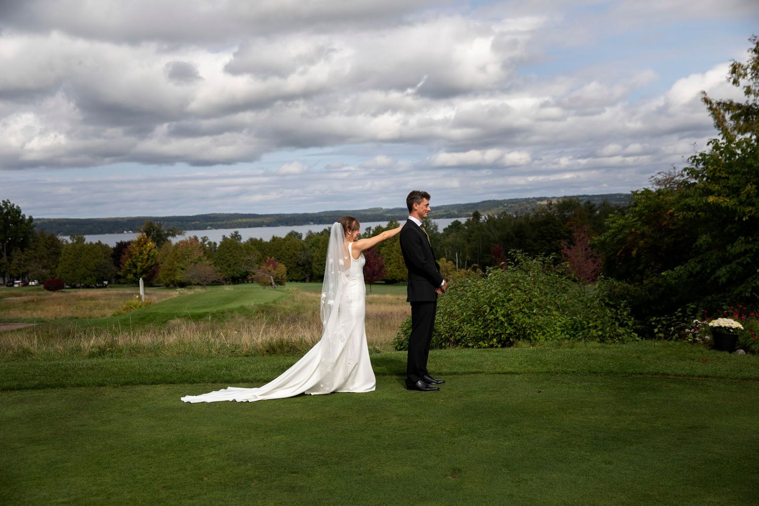 Wedding couple poses in dramatic landscape with cloudy skies and rolling hills.
