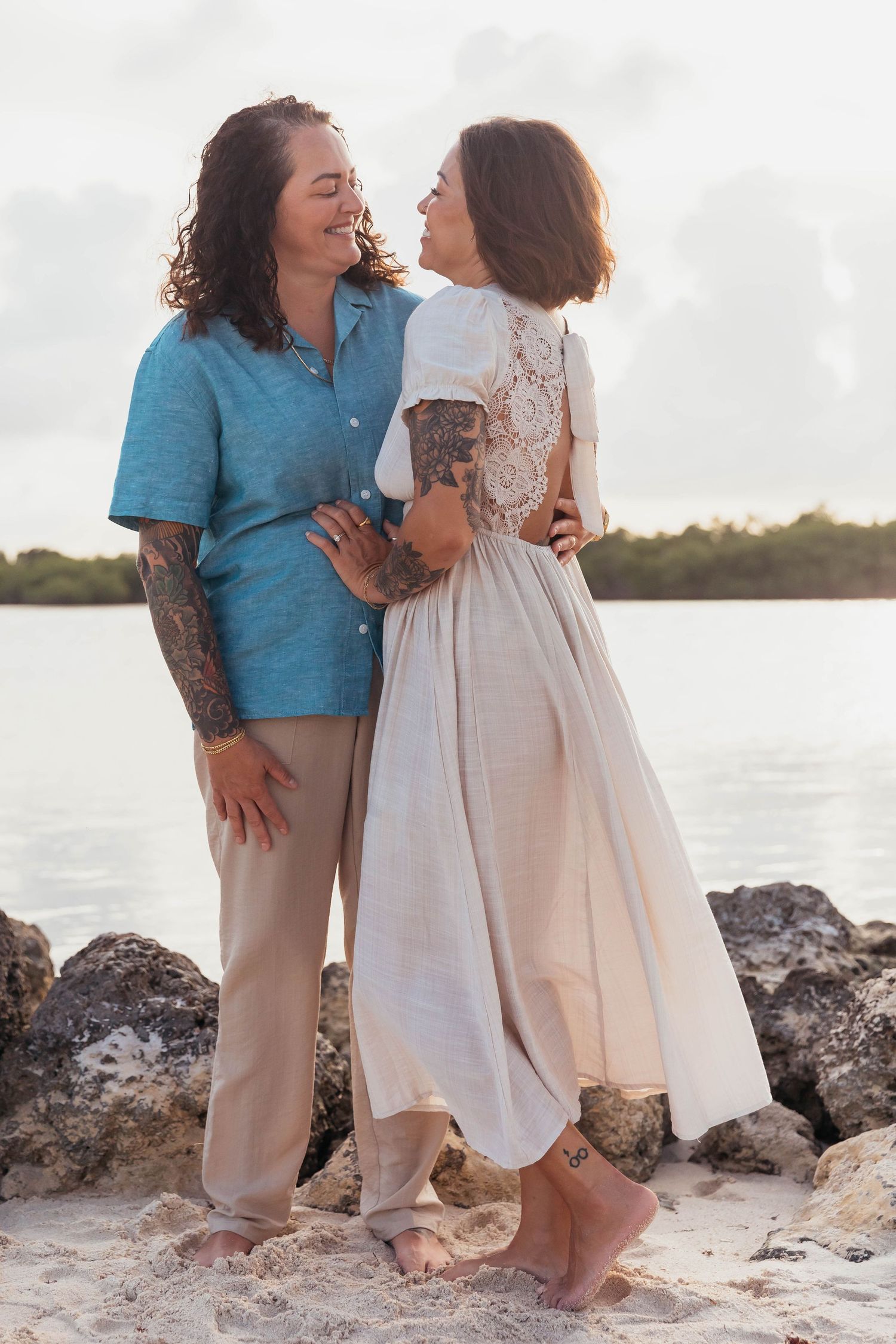 Two people sharing intimate moments on a rocky beach at sunset.