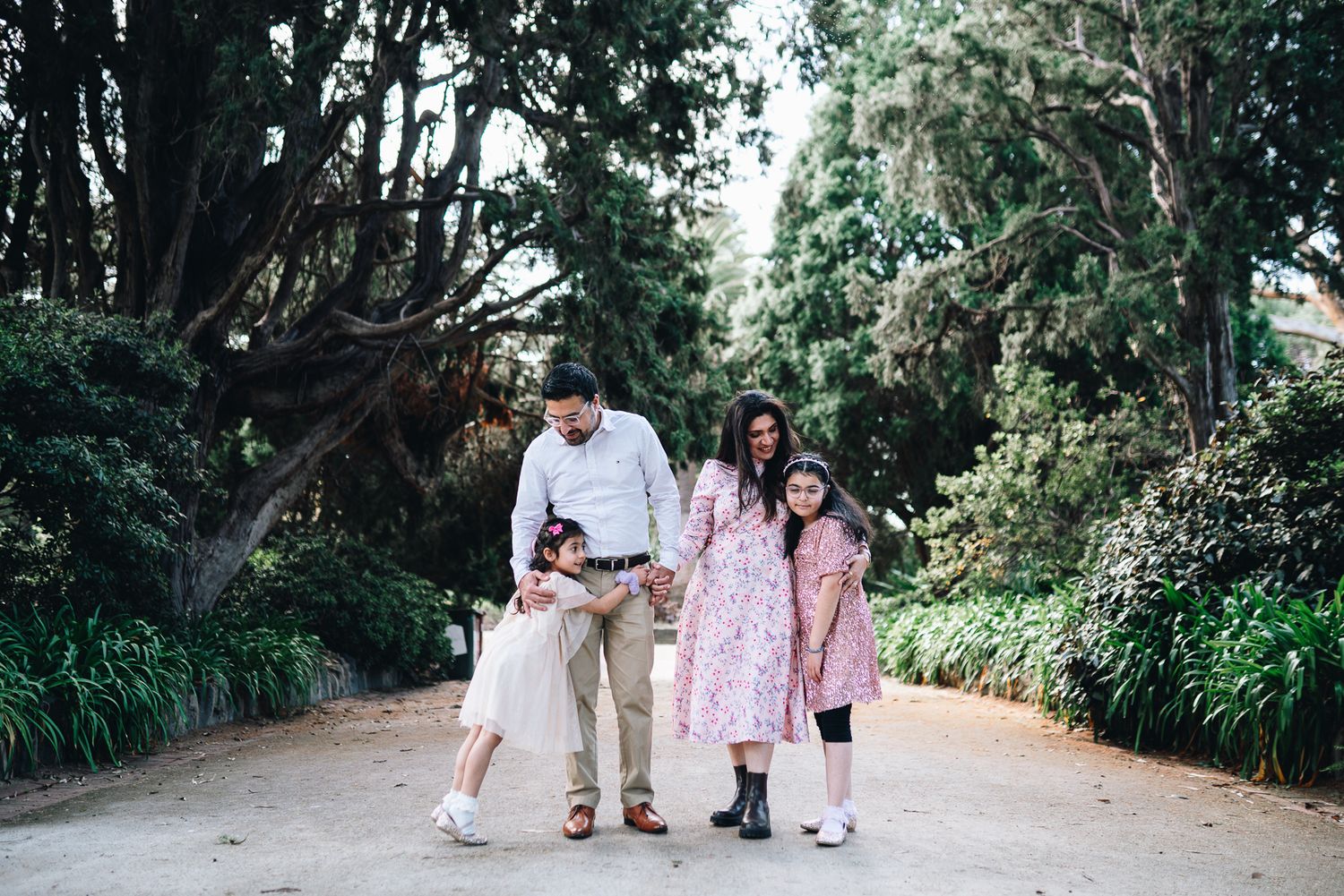 A happy family of 4 in a family photoshoot in Melbourne's St Kilda Botanical Gardens with lush greeneries as backdrop
