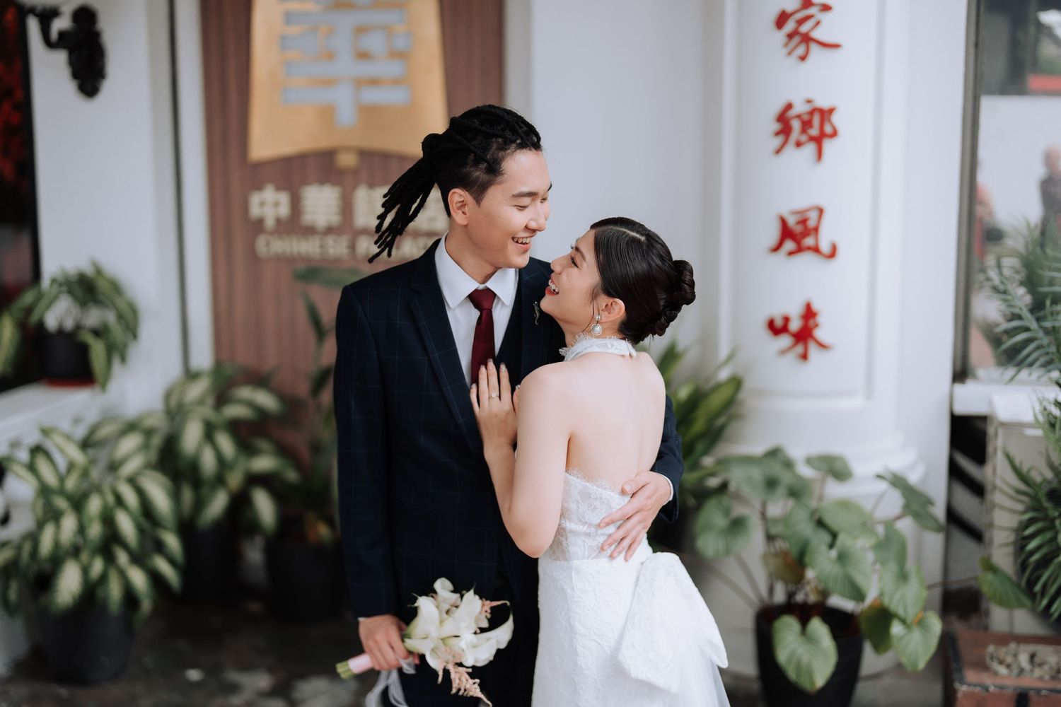 Romantic couple embracing in front of traditional Chinese building with red text.