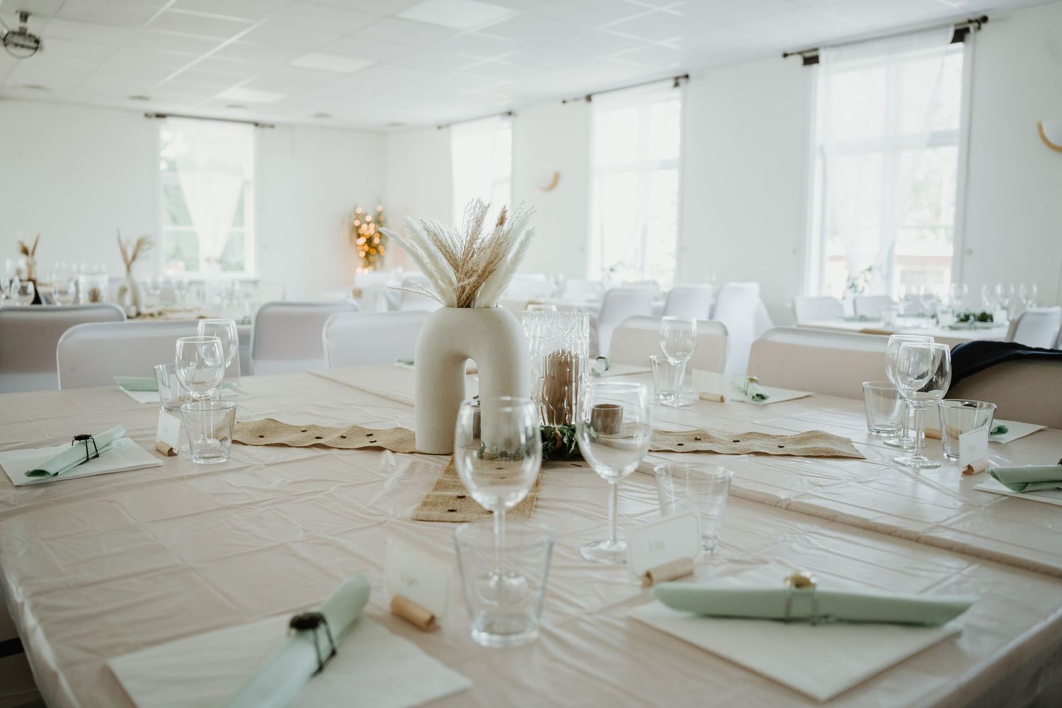 Elegant wedding reception table setting with white linens and dried floral centerpieces.