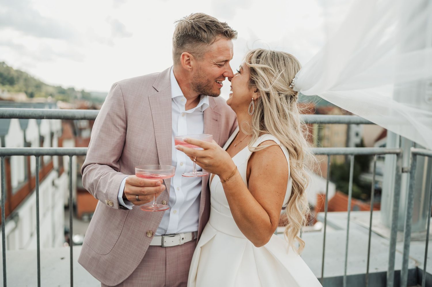 A couple celebrates their wedding day outdoors surrounded by guests on a sunny summer afternoon.