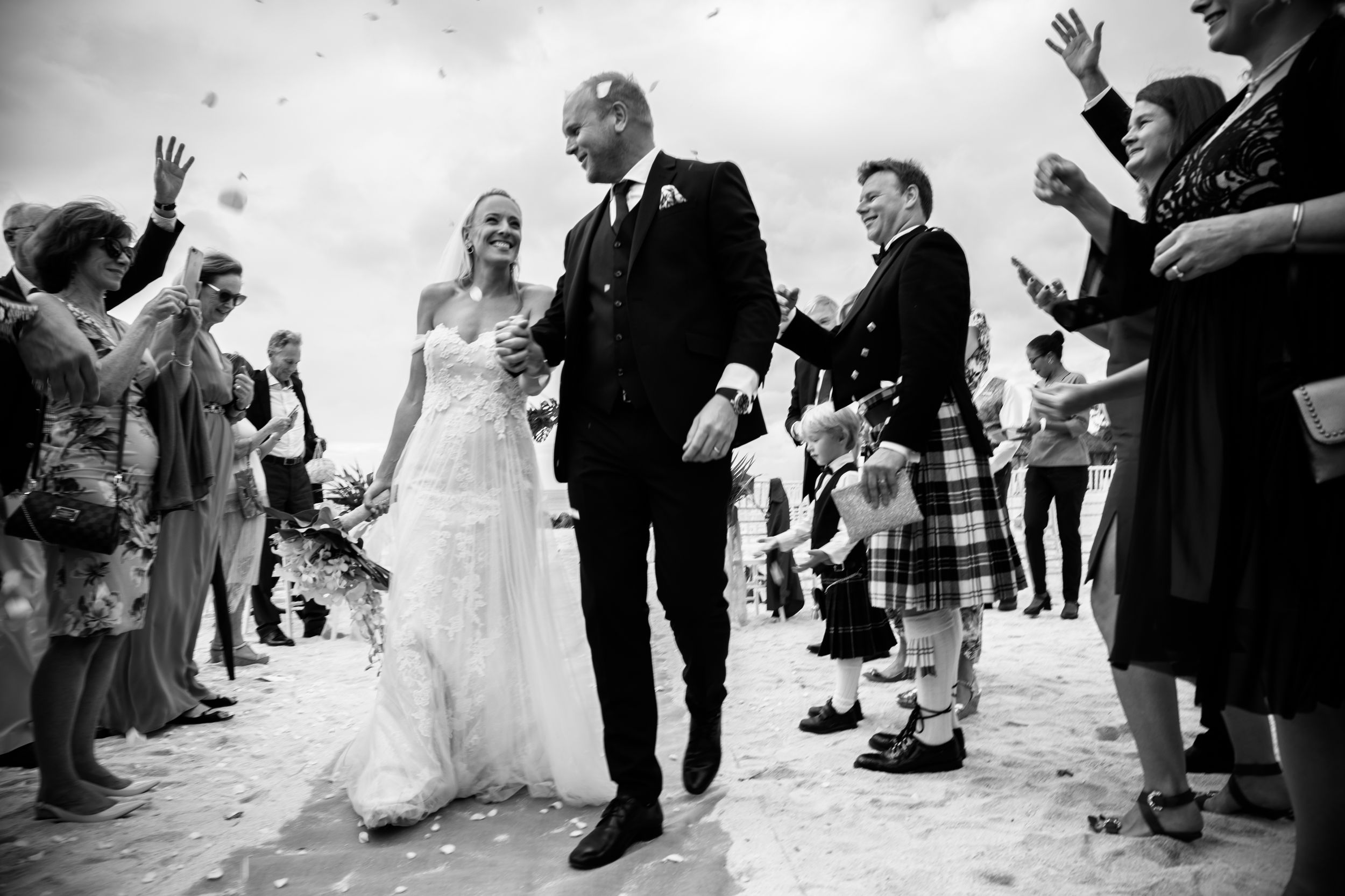 Bride and groom walking out after their beach wedding ceremony in Mauritius surrounded by guests throwing confetti, Luminair Studio wedding