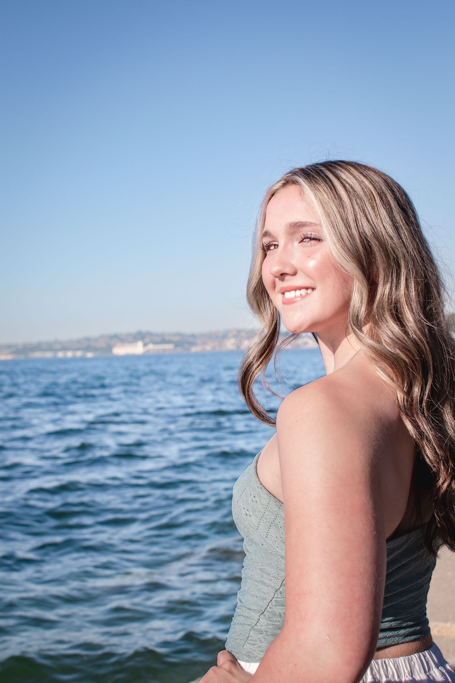 Seattle high school senior photos at Alki Beach during golden hour featuring a senior in a flowy dress