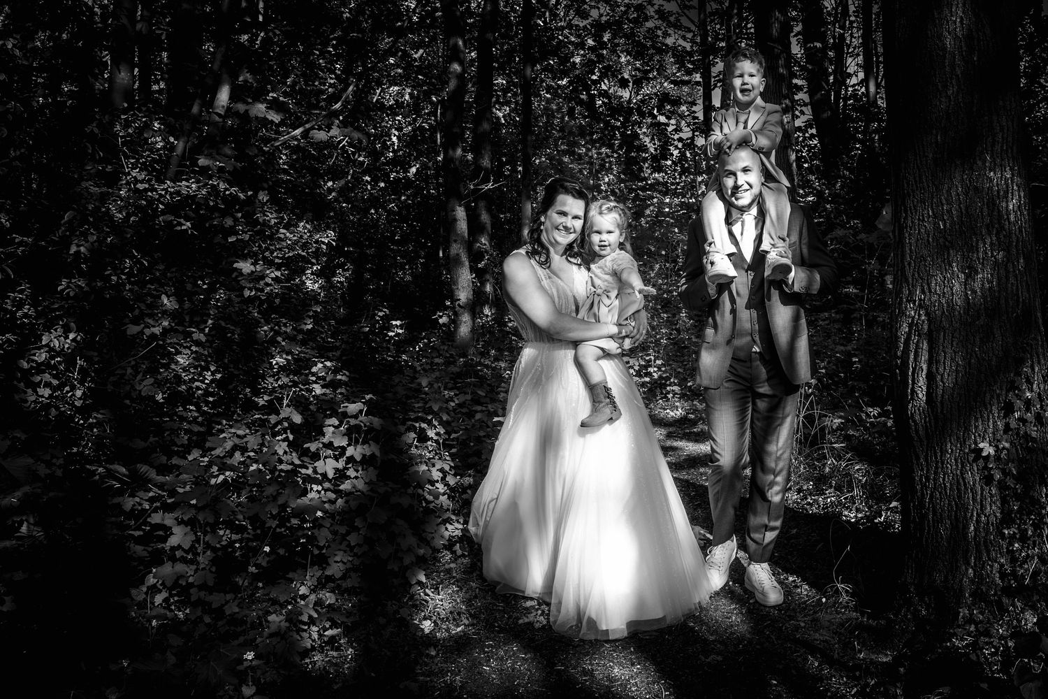 Jesse, Sharon en hun kinderen tijdens een ontspannen familieshoot in het bos bij Zoomers aan het Bos in Castricum, vastgelegd in zwart-wit.