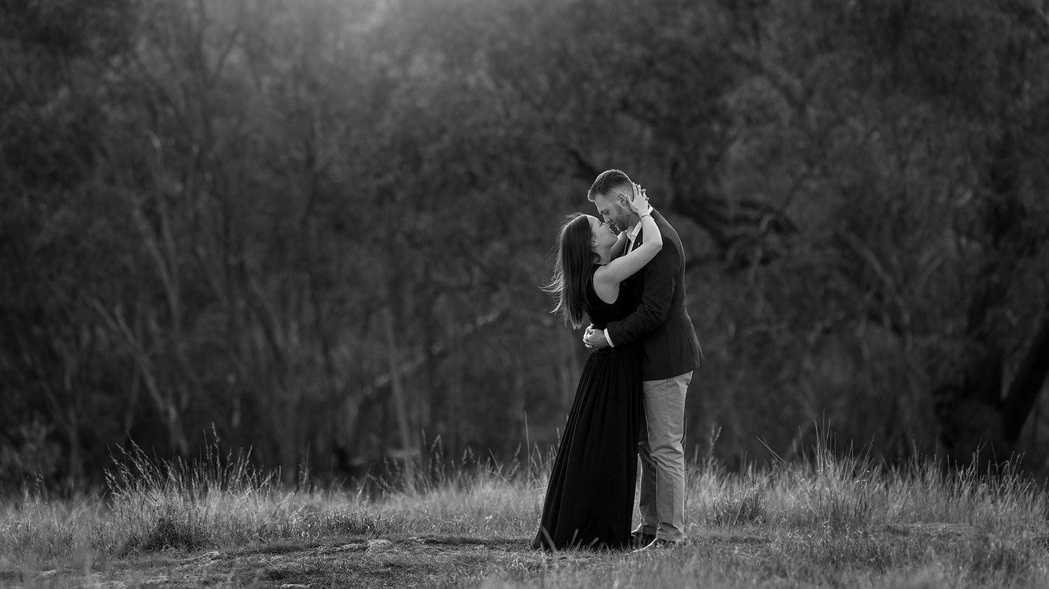 Silhouetted couple embraces during sunset in romantic woodland setting with dramatic lighting and trees at Eastern Hill Lookout in Albury.