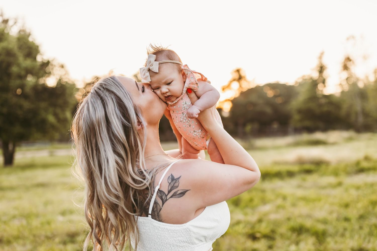 A tender moment between parent and child in a sunlit field during golden hour.