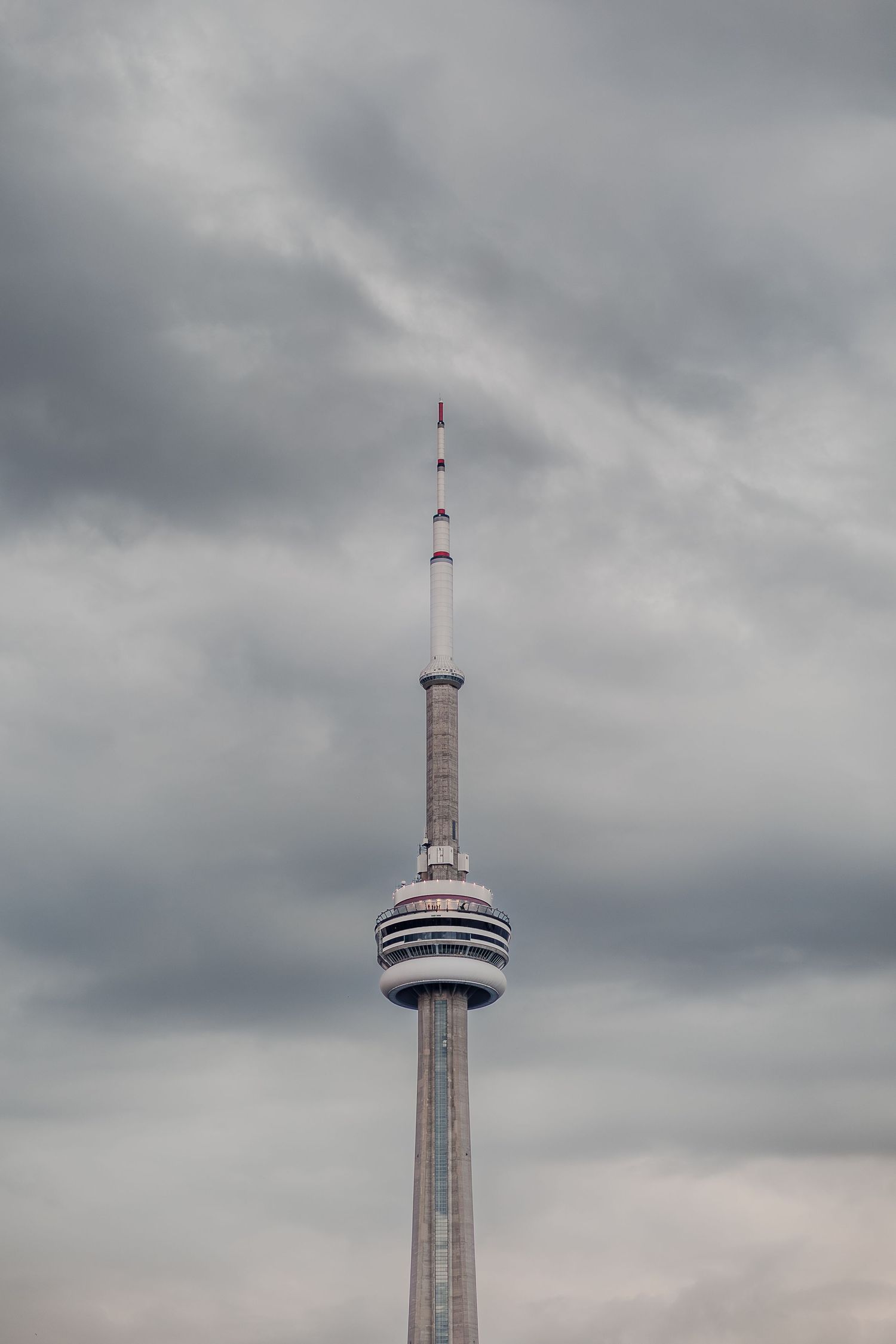 Multiple tall towers and antennas rise against a cloudy gray sky.