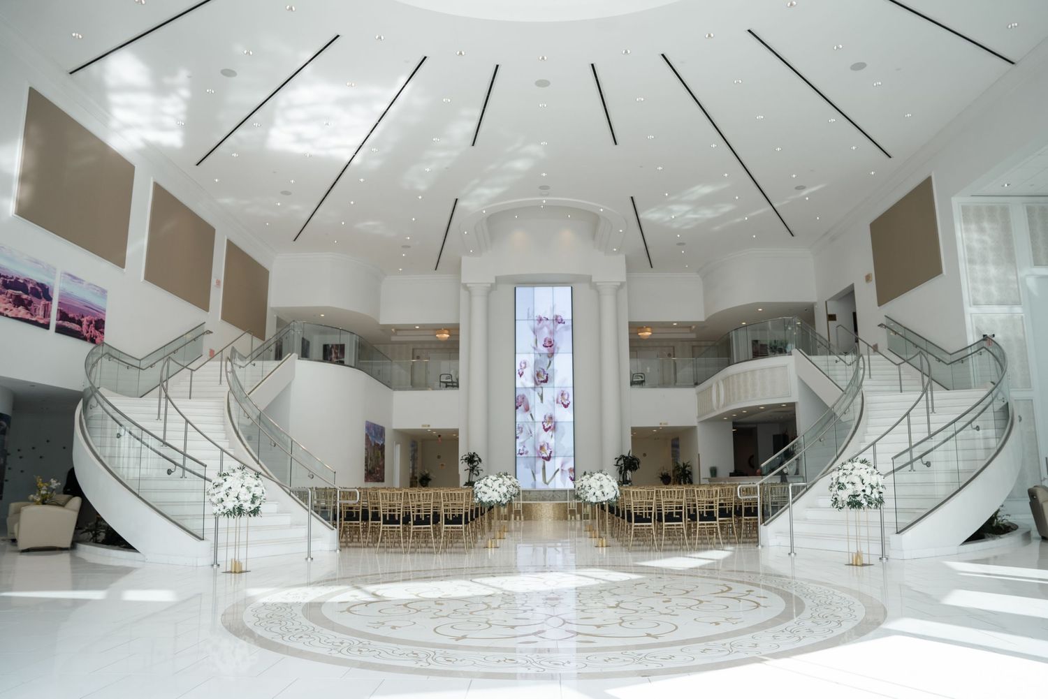 Modern circular atrium with spiral staircase and white interior design features curved railings and natural lighting.
