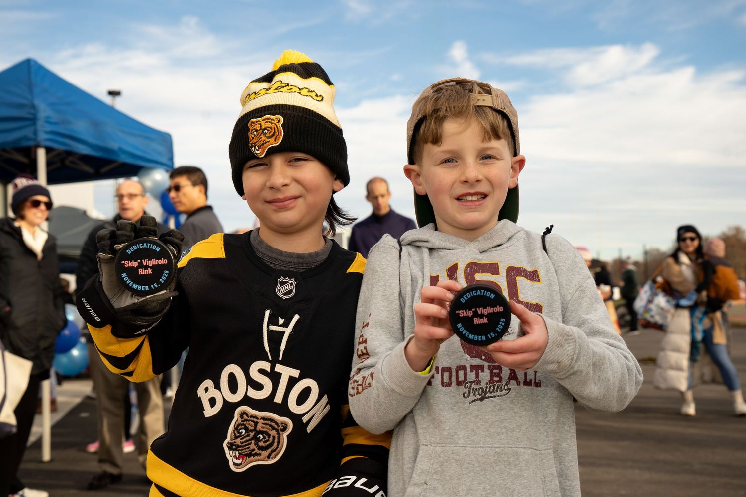 kids celebrate with pucks at Belmont’s Skip Viglirolo Ice skating Rink Grand Opening - Leah Ramuglia Photography