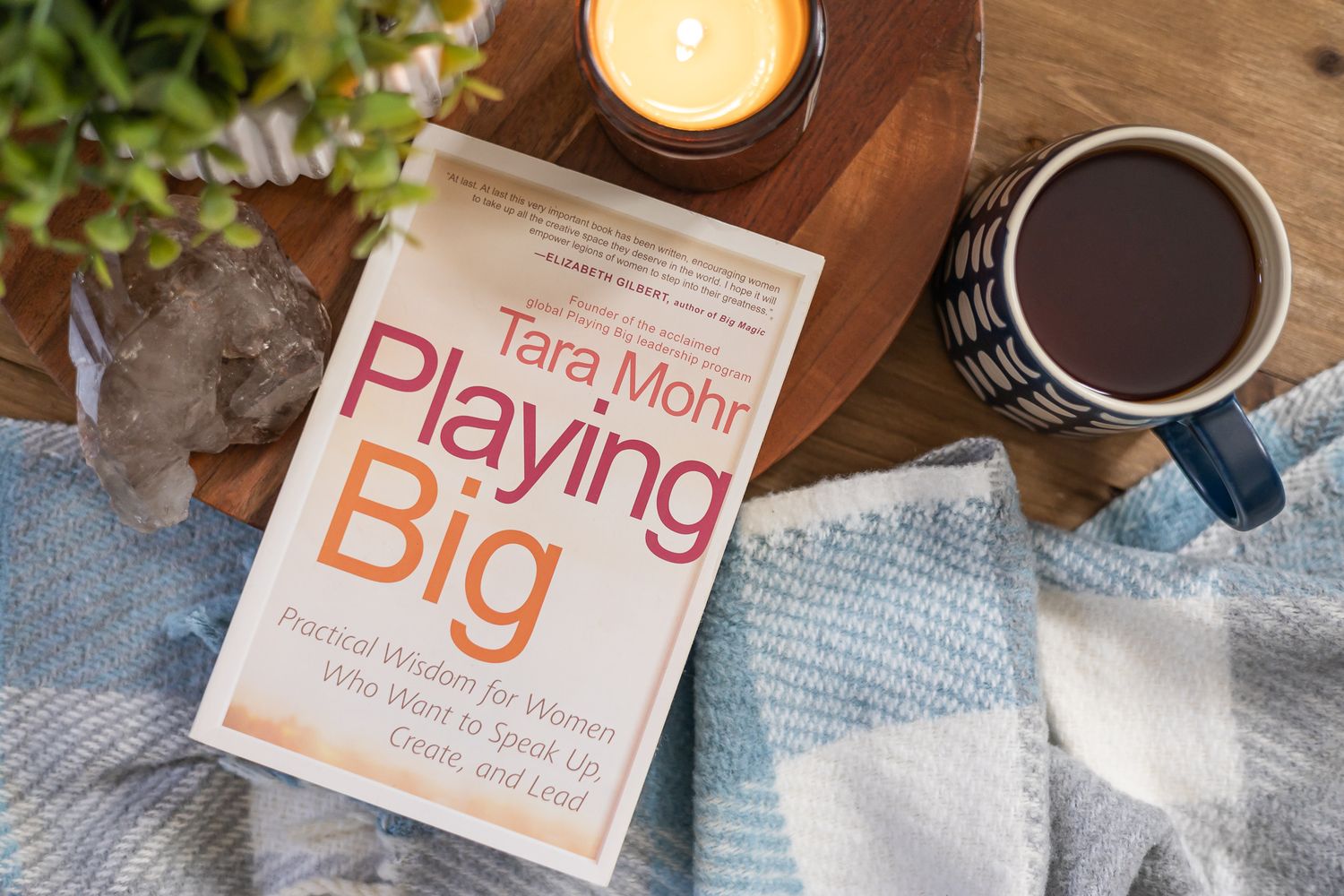 staged flat lay overhead book Playing Big by Tara Mohr on blanket with candle, plant, crystal and cup of tea on table in Seattle, WA