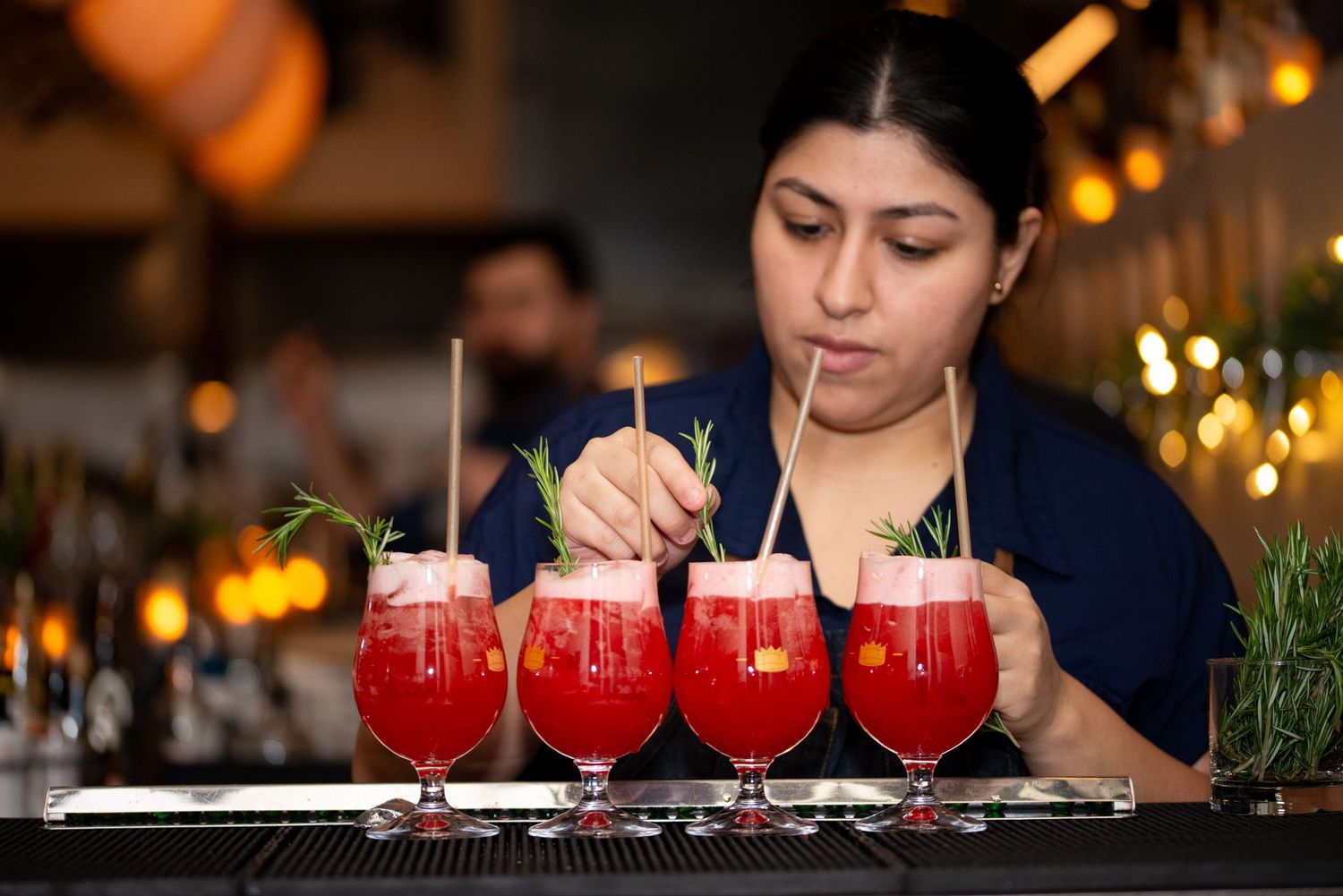 A row of vibrant red cocktails garnished with rosemary sprigs at Branch Line in Watertown’s Arsenal, Event Photography by Leah Ramuglia