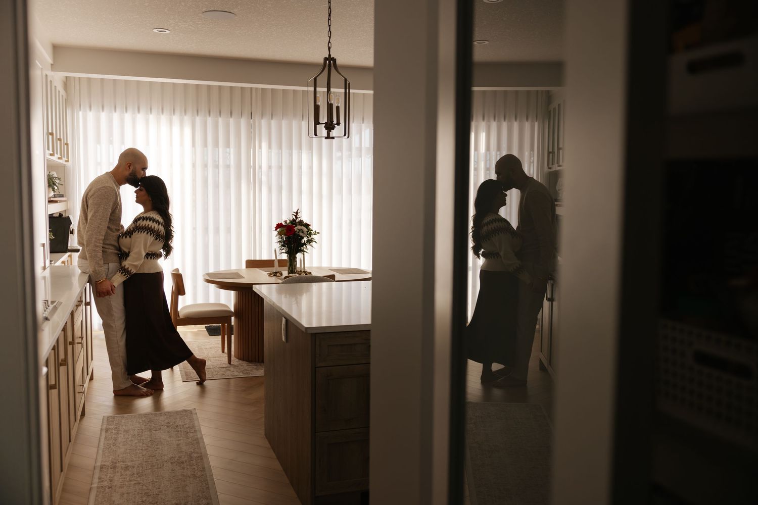 Silhouettes of couple in hallway with moving boxes and natural lighting.