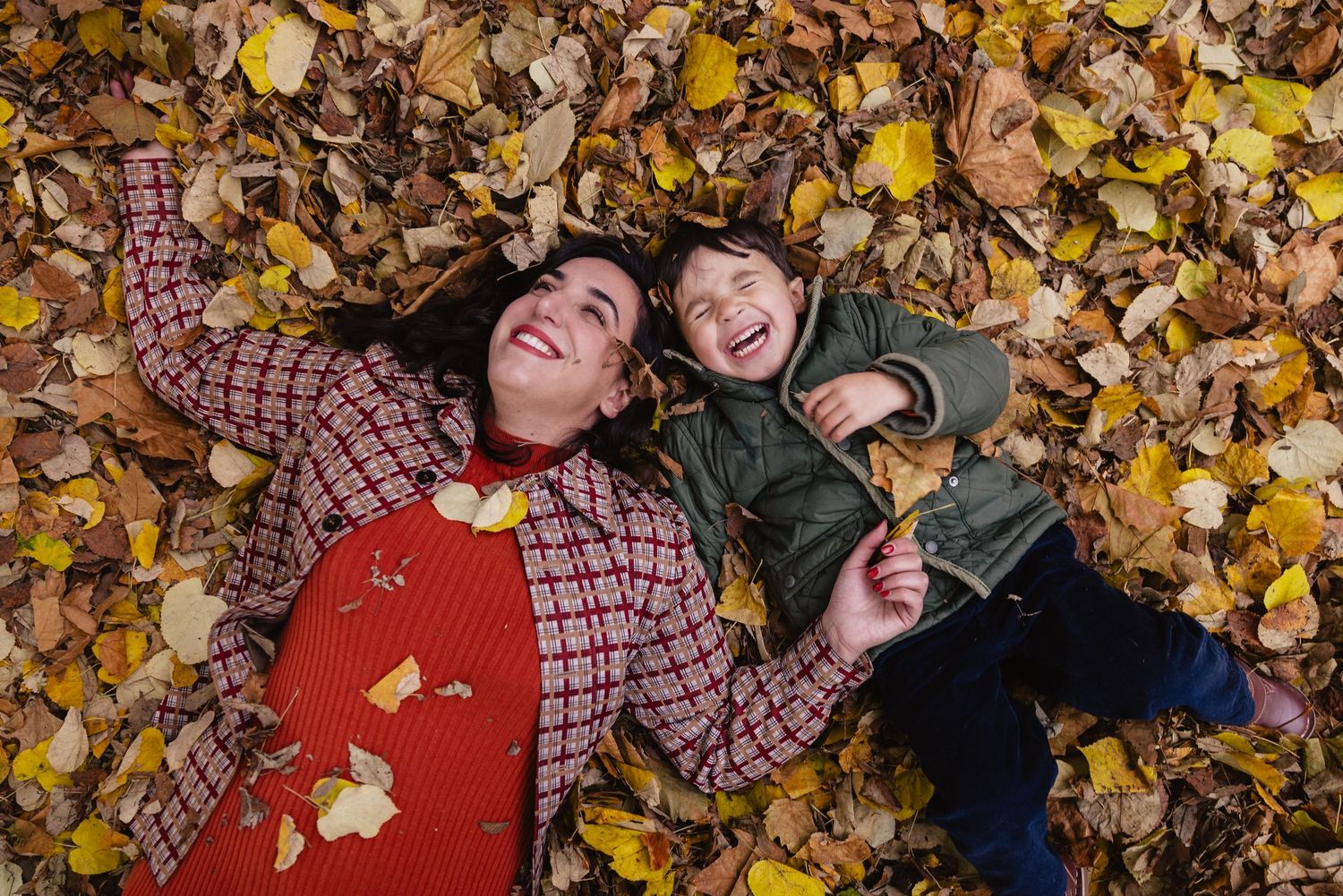 Une maman et son fils se roulent dans un tas de feuilles mortes lors d'une séance photo famille à Courbevoie