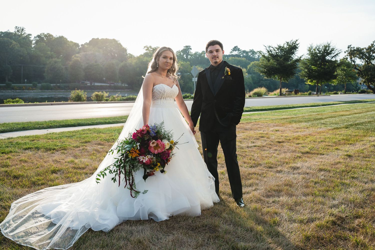 A couple walking and laughing together outdoors, with the bride's white dress flowing in the wind.
