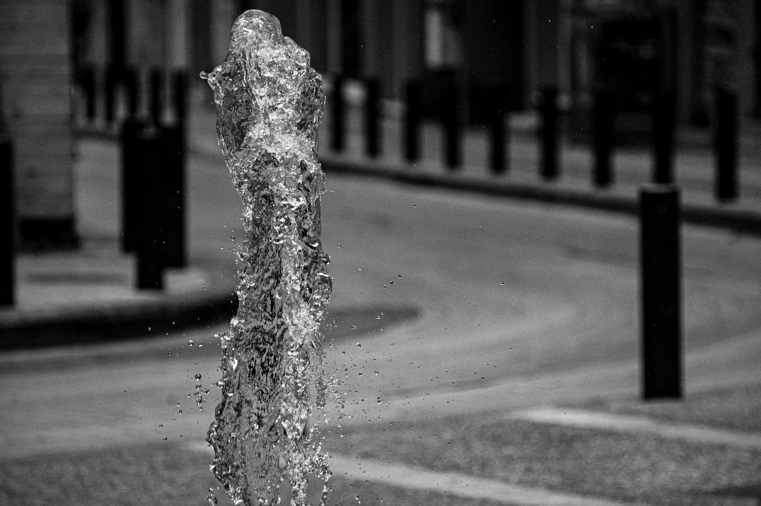 Water droplets falling in slow motion against a blurred urban street background with lampposts and buildings.