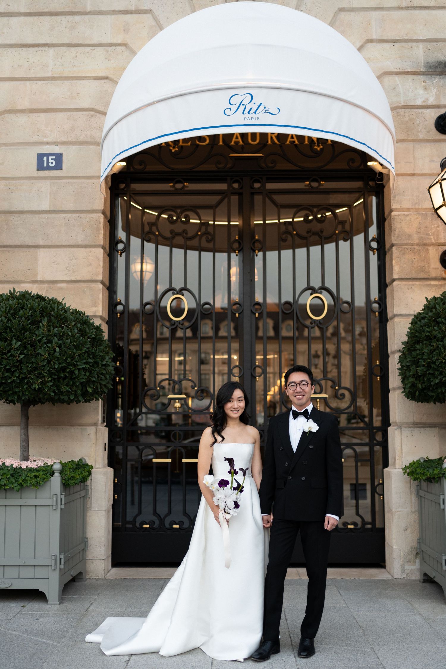Bride and groom posing in front of the Ritz Paris entrance gates on their wedding day.