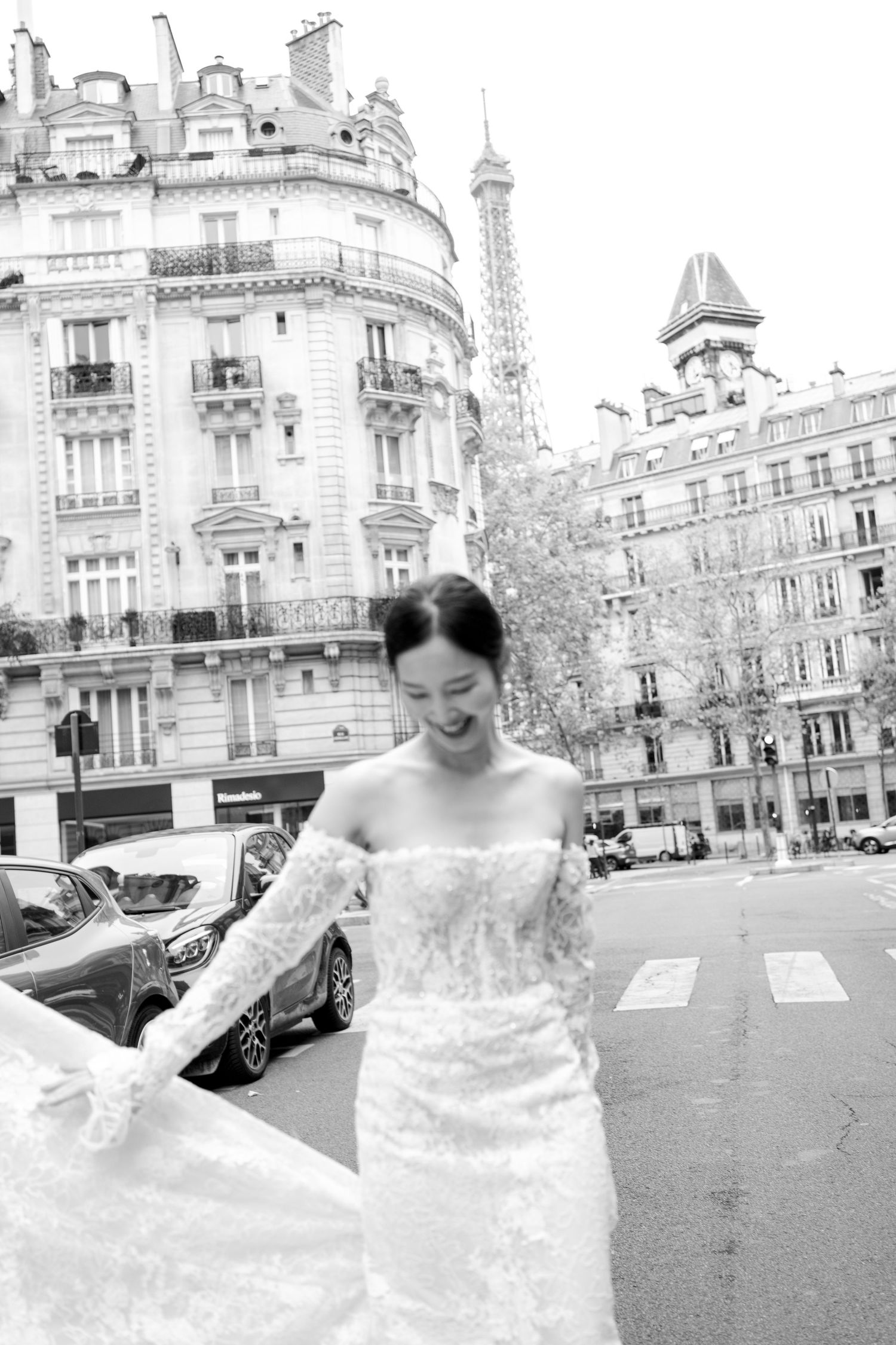 A couple in wedding attire poses romantically on a Paris street with the Eiffel Tower visible in the background. Paris editorial wedding