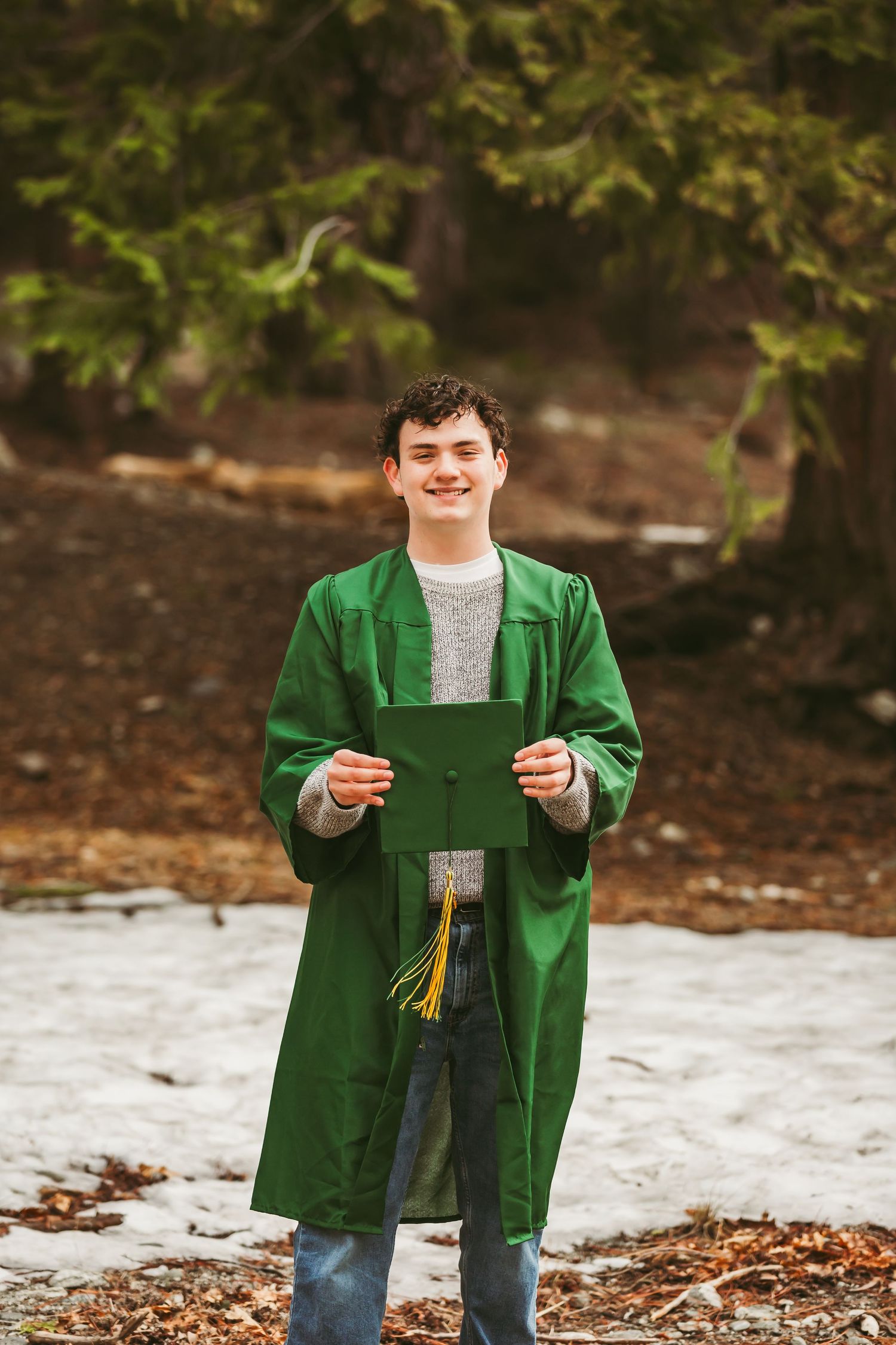 Graduate in bright green graduation gown holds diploma while standing outdoors in fall setting.